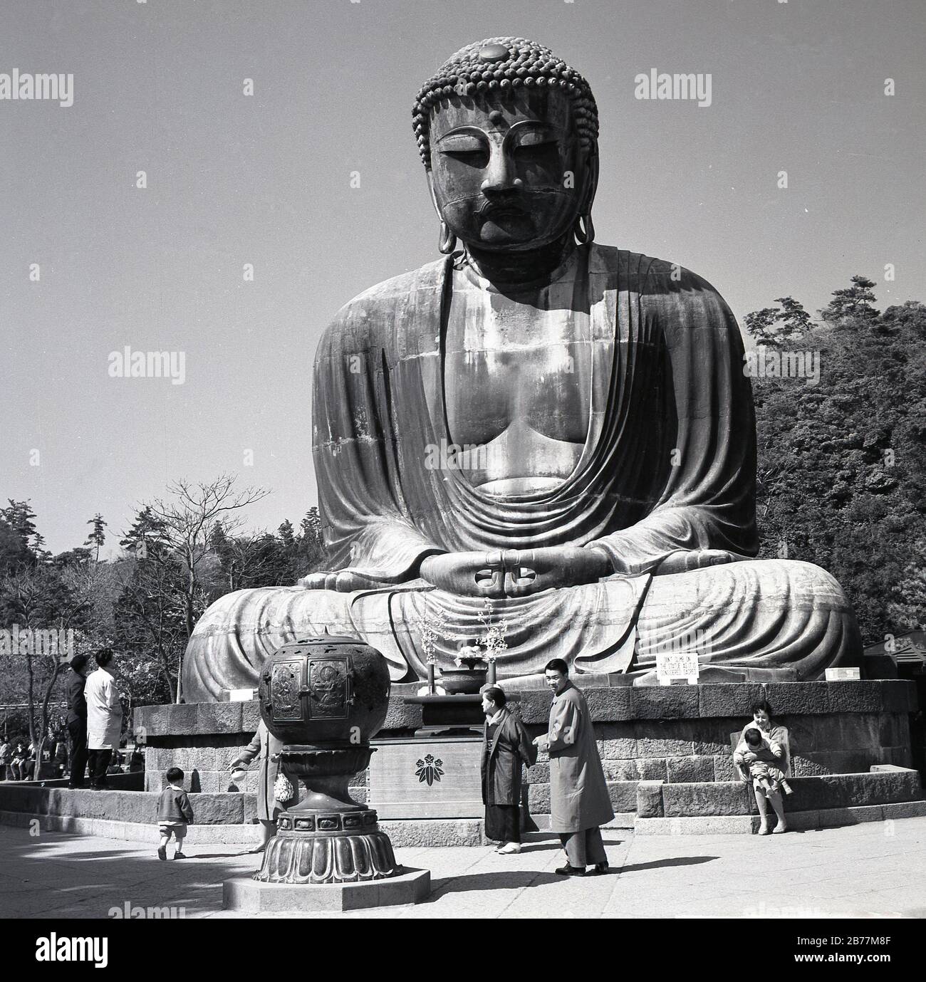 Anni '50, storico, i visitatori della sacra statua di bronzo, il Grande Buddha di Kamakura, Giappone, che si erge sui terreni del Tempio di Kotoku-in e un punto di riferimento storico nel paese risalente al 1252. Foto Stock