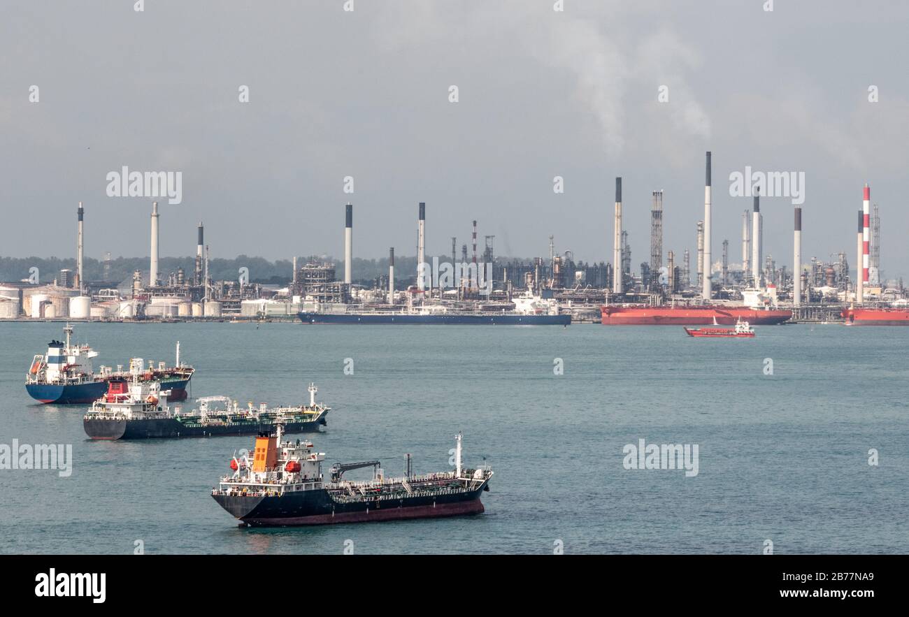 Navi nello stretto di Malacca presso l'enorme complesso di raffineria di petrolio a Singapore Foto Stock