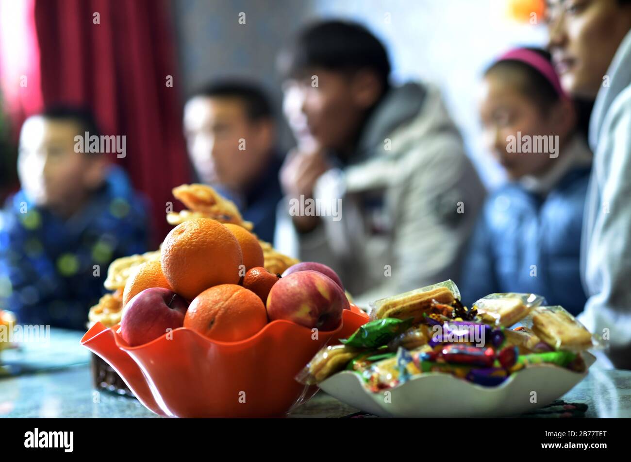 (200314) -- LHASA, 14 marzo 2020 (Xinhua) -- Frutta e spuntini sono messi sul tavolo quando la 'famiglia' di Pandor guarda la televisione in una casa per bambini a Lhasa, regione autonoma del Tibet della Cina sudoccidentale, 11 marzo 2020. Pandor nacque a Shigatse, nella regione autonoma del Tibet della Cina sudoccidentale, una città vicina al confine con Nepal, Bhutan e India. È orgogliosa di essere una 'madre' di 22 bambini, anche se i 37 anni non sono mai stati incinta o sposati. Sei anni fa, Pandor si trasferì nella capitale regionale, Lhasa, dove trovò un lavoro in una casa per bambini per i neonati fino allo studio universitario Foto Stock