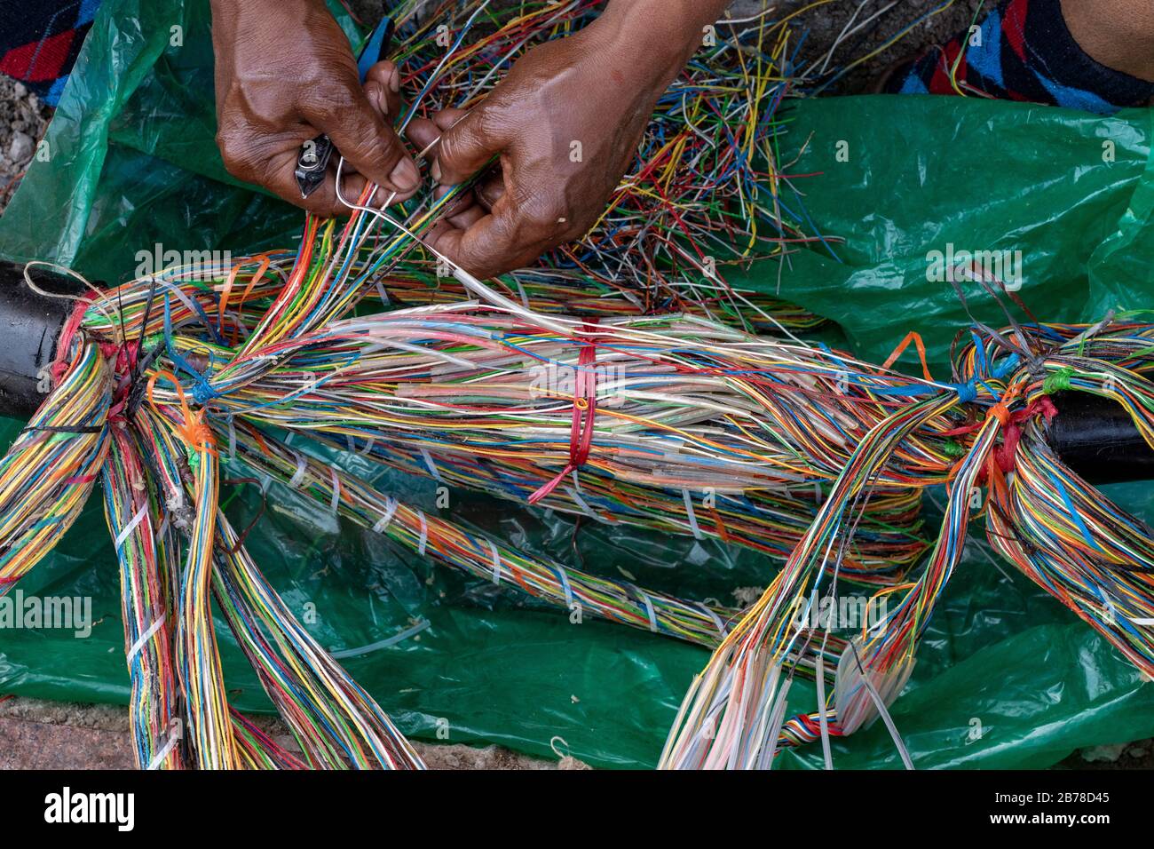 Tecnico che ripara una linea telefonica sotterranea con fili multicolore Foto Stock