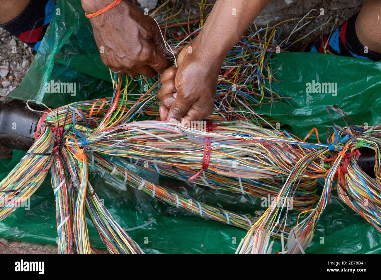 Tecnico che ripara una linea telefonica sotterranea con fili multicolore Foto Stock