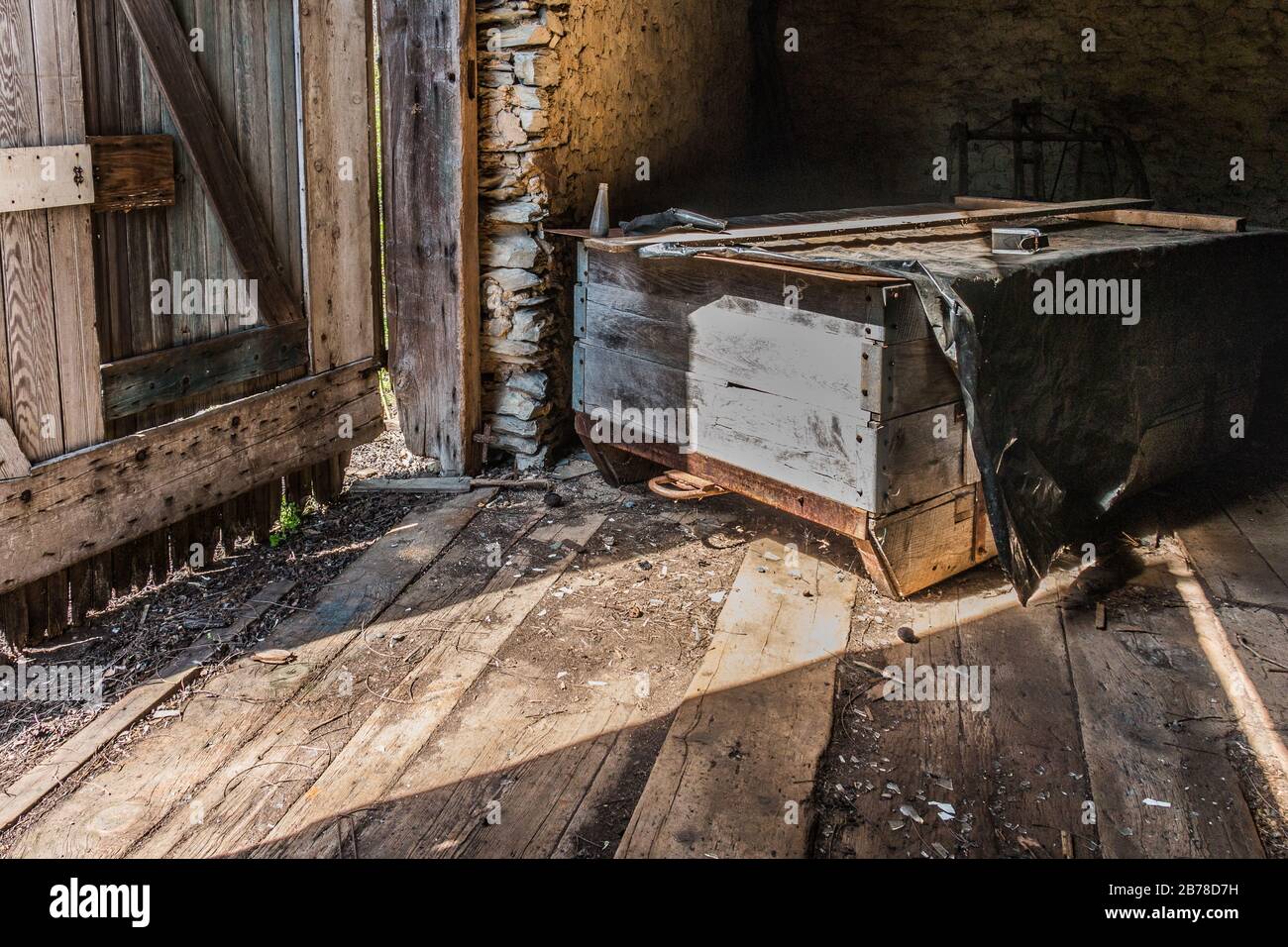 Interno grezzo-cucito di un vecchio fienile in legno nella Pennsylvania orientale con attrezzi agricoli antichi Foto Stock
