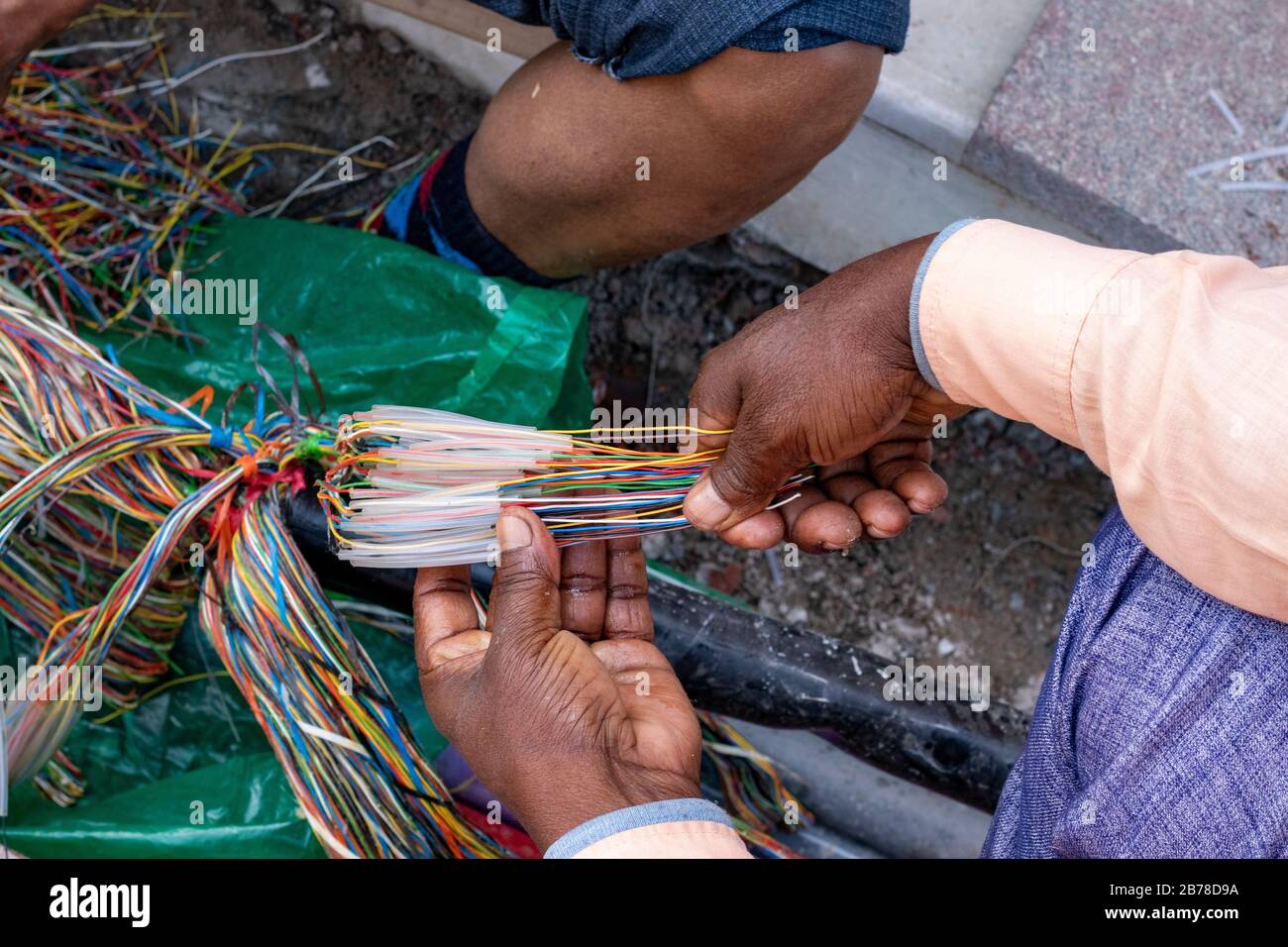 Tecnico che ripara una linea telefonica sotterranea con fili multicolore Foto Stock