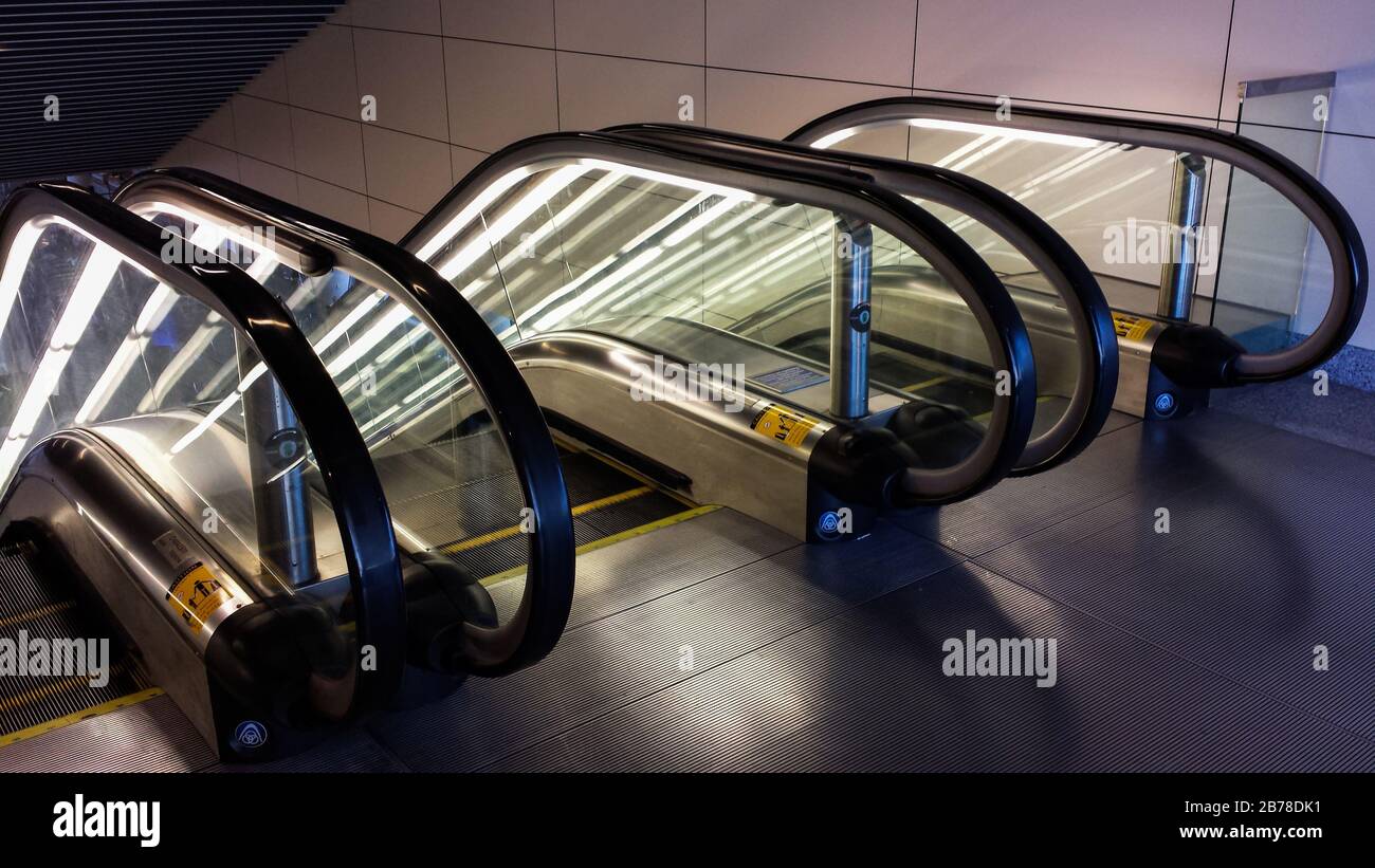 Scale mobili all'aeroporto DFW con riflessi luminosi di luci fluorescenti nel vetro e sul pavimento piastrellato Foto Stock