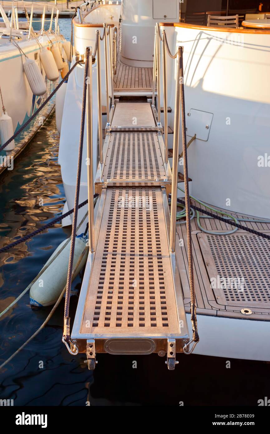 Extended passerella telescopica tra dock e barca per un facile accesso. La passerella è in teak; alluminio e corde. Foto Stock