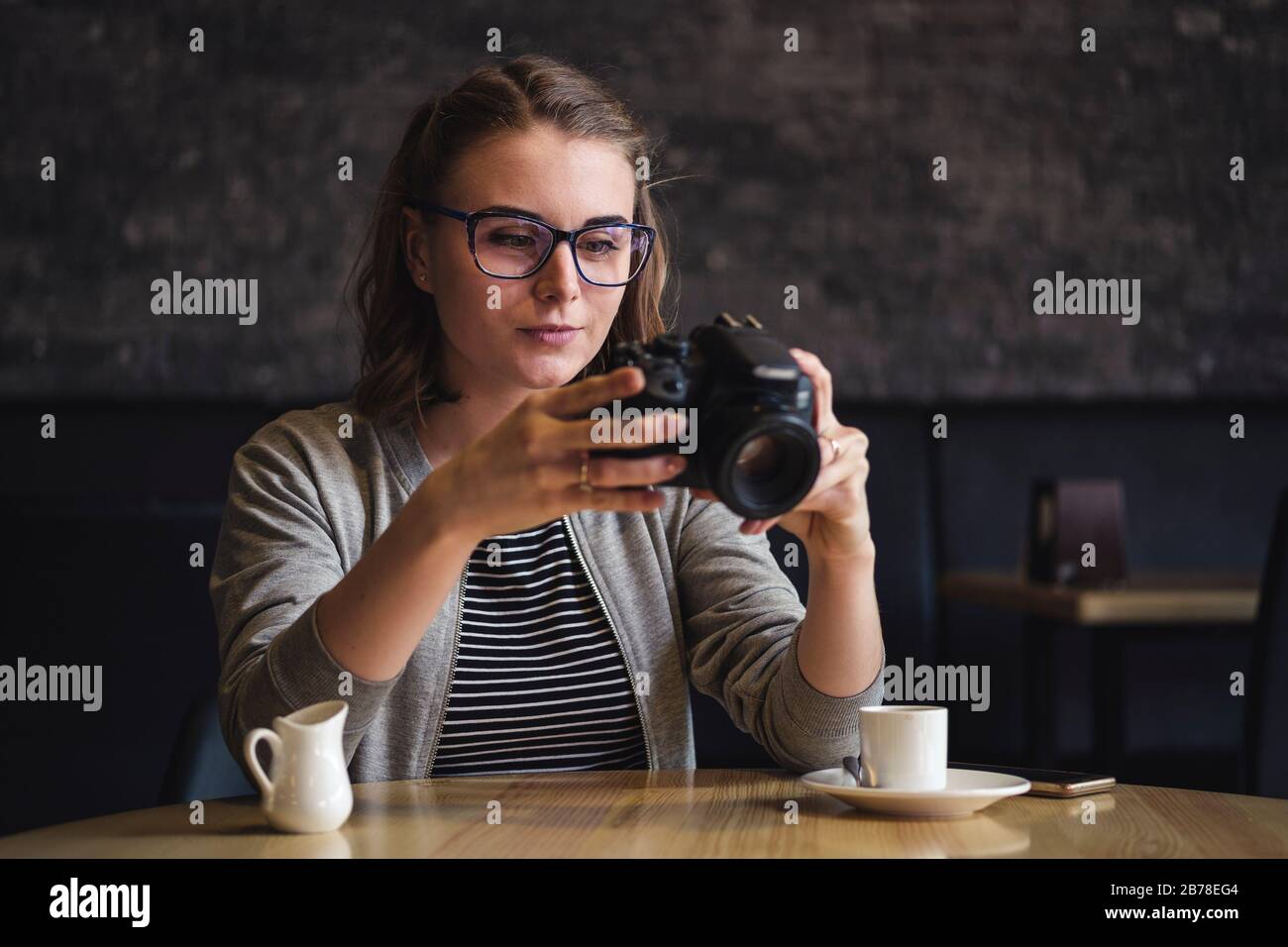Giovane fotografo femminile che controlla un'immagine in una caffetteria Foto Stock