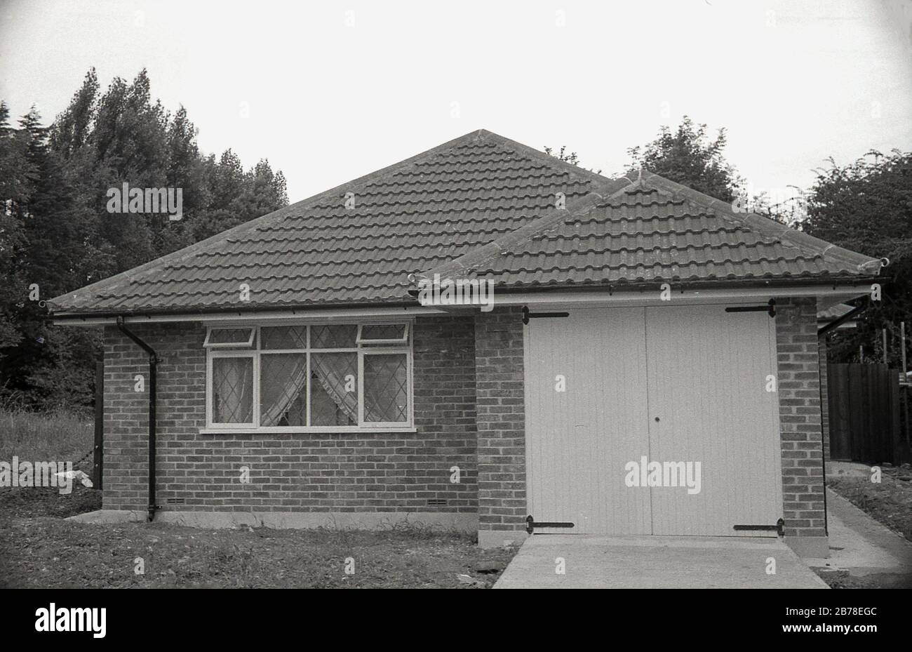 Fine degli anni '60, forse primi anni '70 nuova casa di mattoni a piano singolo, con tetto intitolato, un bungalow, di recente costruzione, con unico garage integrale, Inghilterra, Regno Unito. Foto Stock