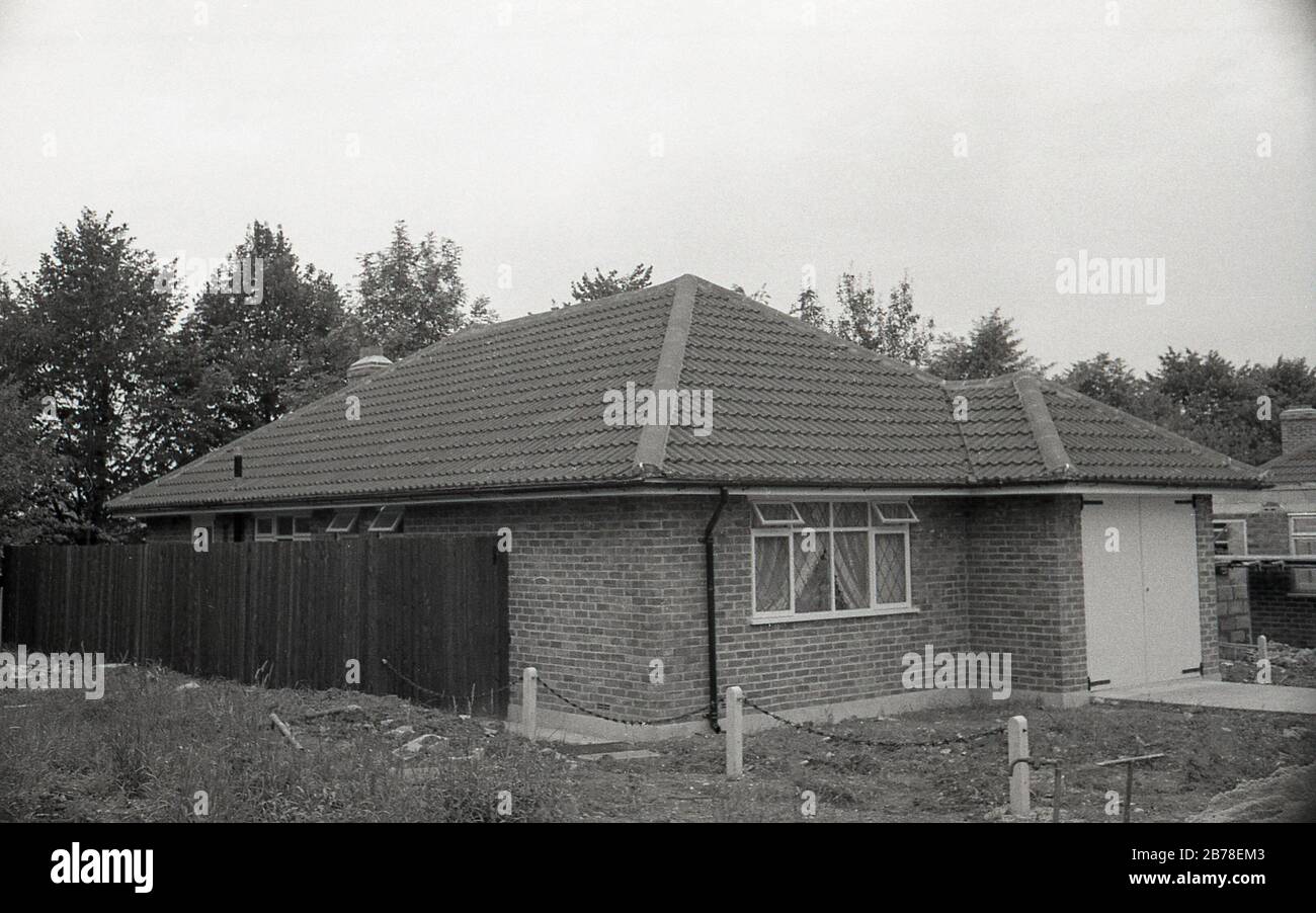 Fine degli anni '60, forse all'inizio degli anni '70, una nuova abitazione a piano singolo, un bungalow, recentemente costruito con garage intergral, in mattoni e con tetto piastrellato, Inghilterra, Regno Unito. Foto Stock