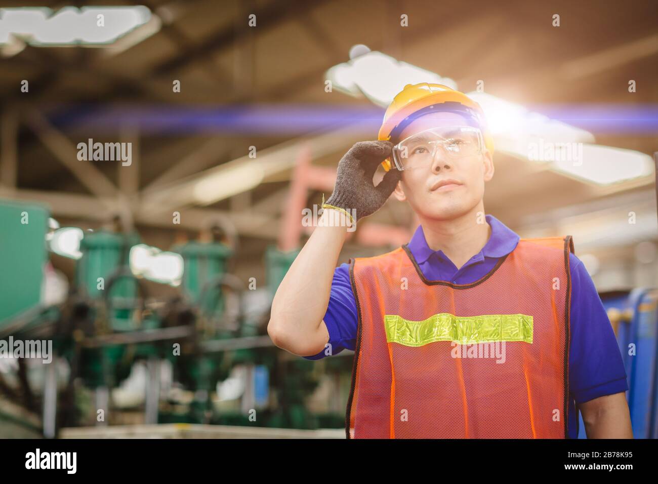 Ritratto di ingegnere intelligente Asian cinese felice lavoratore modello bello in industria pesante background.Hand a occhiali di protezione. Foto Stock