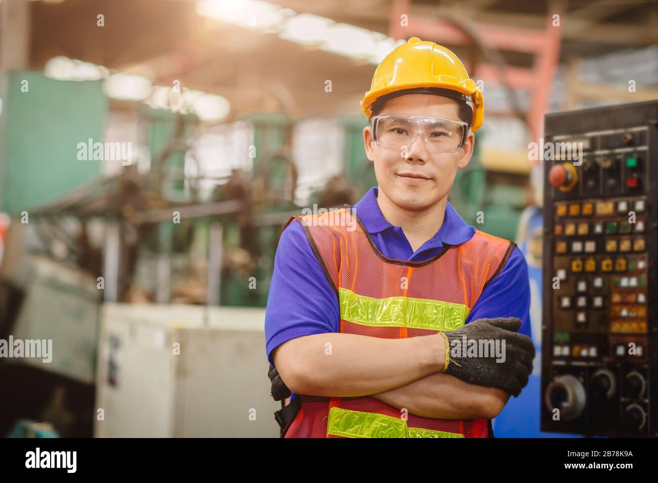 Ritratto di ingegnere intelligente Asian cinese felice lavoratore modello bello in industria pesante background.ARM piegato croce e sorridente. Foto Stock