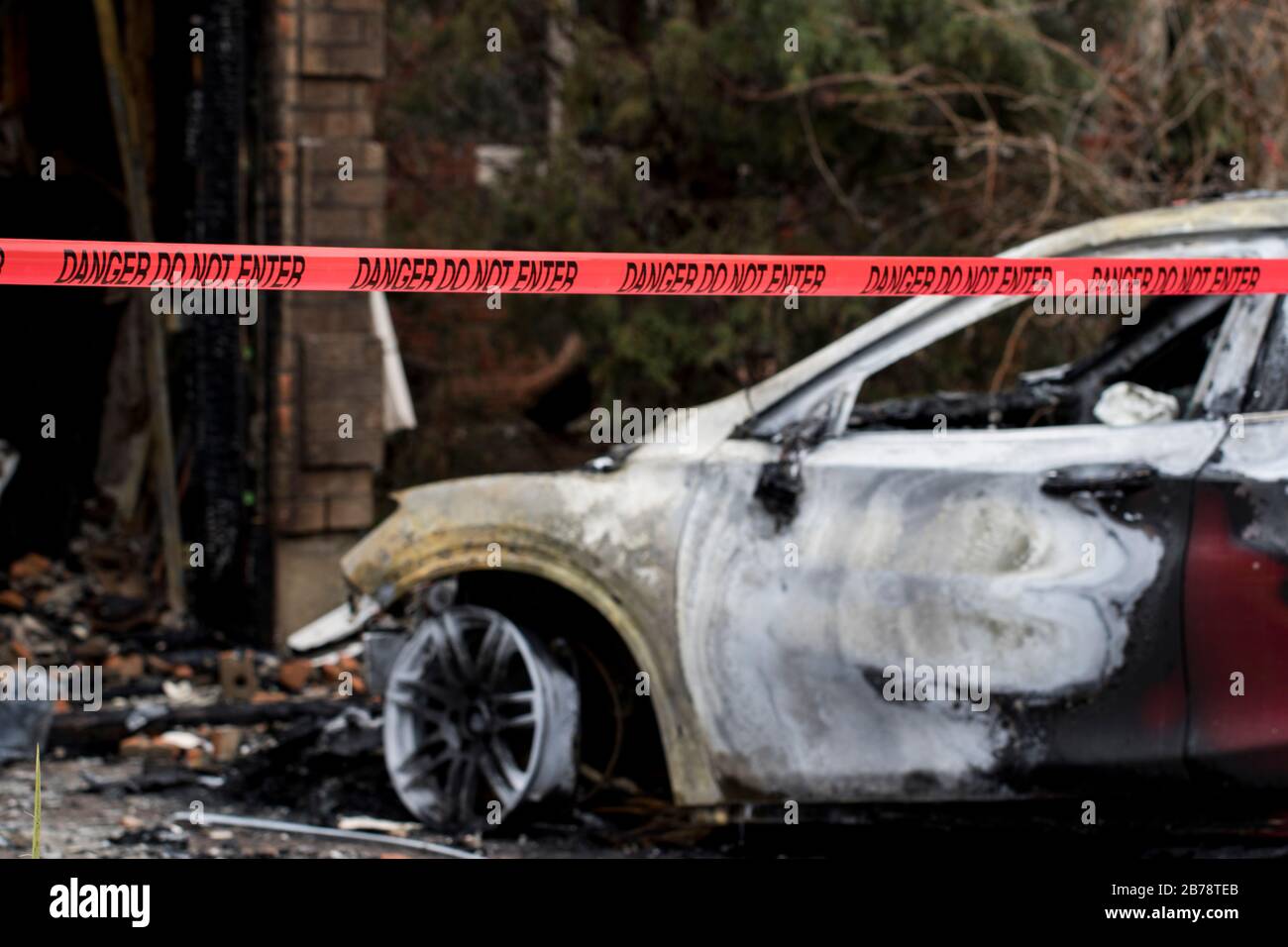 Incendio dell'automobile veicolo bruciato distrutto da un incendio di grandi dimensioni. Resti incendiati di un veicolo con nastro di reato dopo Arson. Macchina bruciata dopo il fuoco. Foto Stock