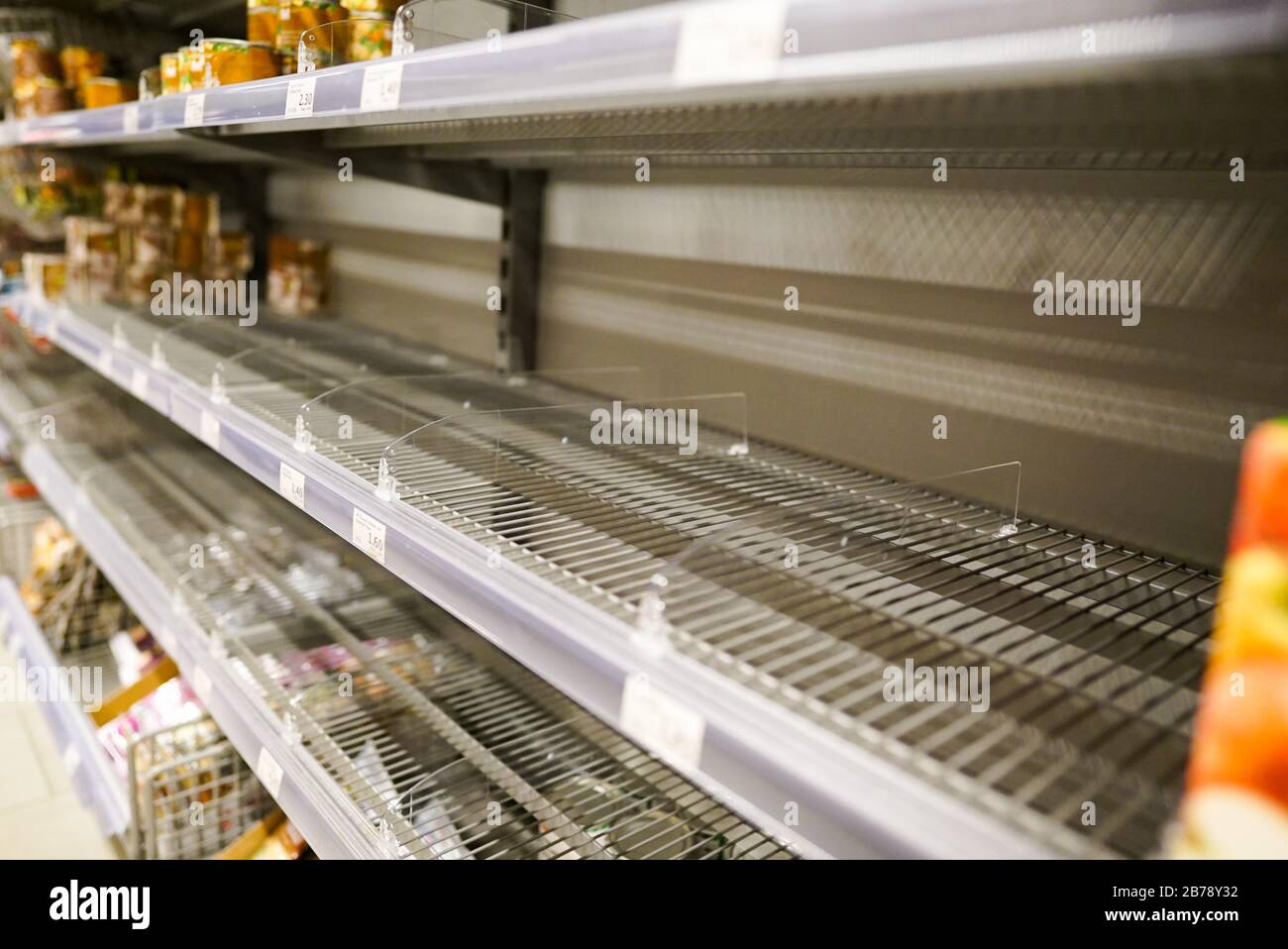 Molti scaffali vuoti con pochi prodotti in scatola lasciati in un supermercato Eurpean a causa di panico shopping a causa del virus Covid-19 Foto Stock