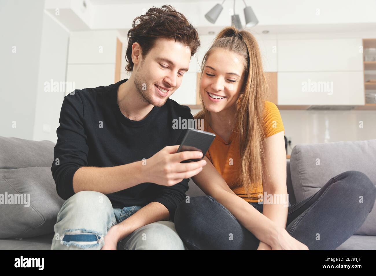 Accoppia usando il Internet di casa veloce con il telefono intelligente. Donna e uomo che usano i social media. Foto Stock