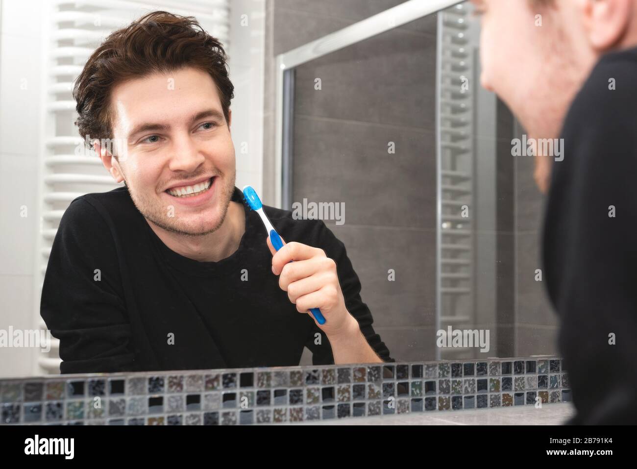 Uomo che sfrega i denti in bagno. Concetto di salute dentale Foto Stock