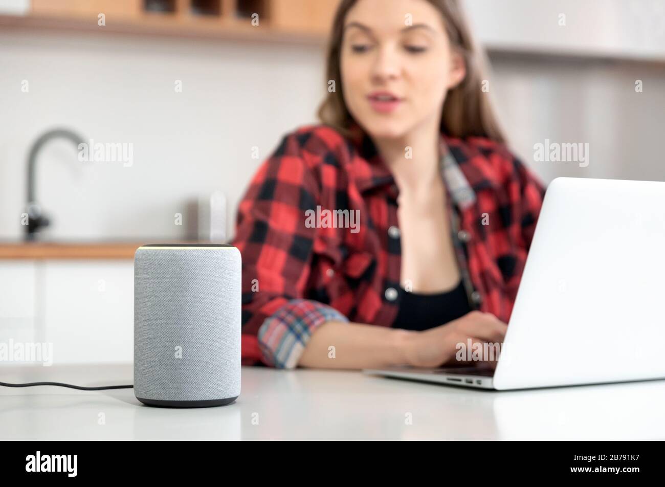 Donna che parla con un altoparlante intelligente. Assistente intelligente nel sistema domestico intelligente. Foto Stock