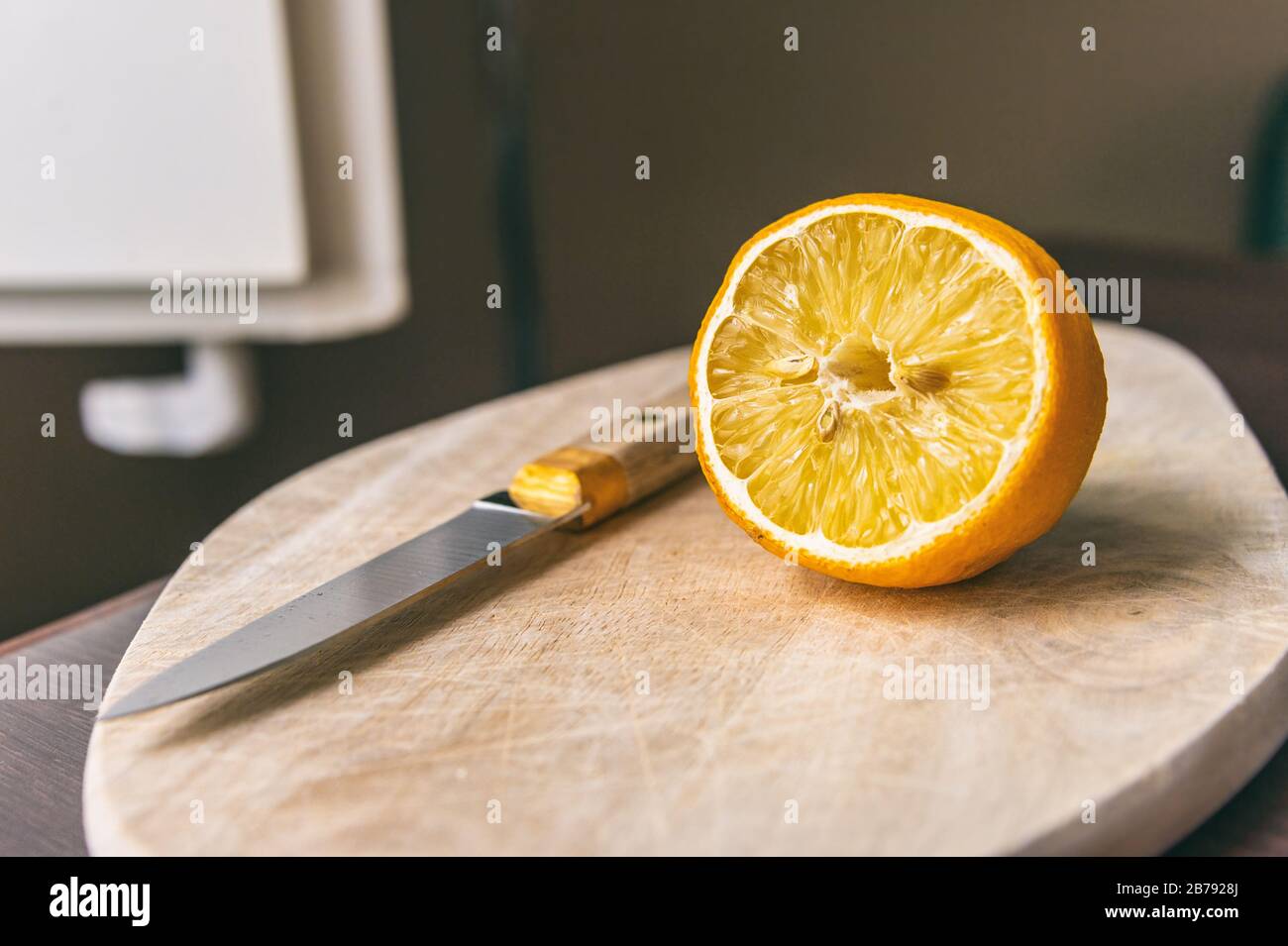 Mezzo limone e coltello su un tagliere Foto Stock