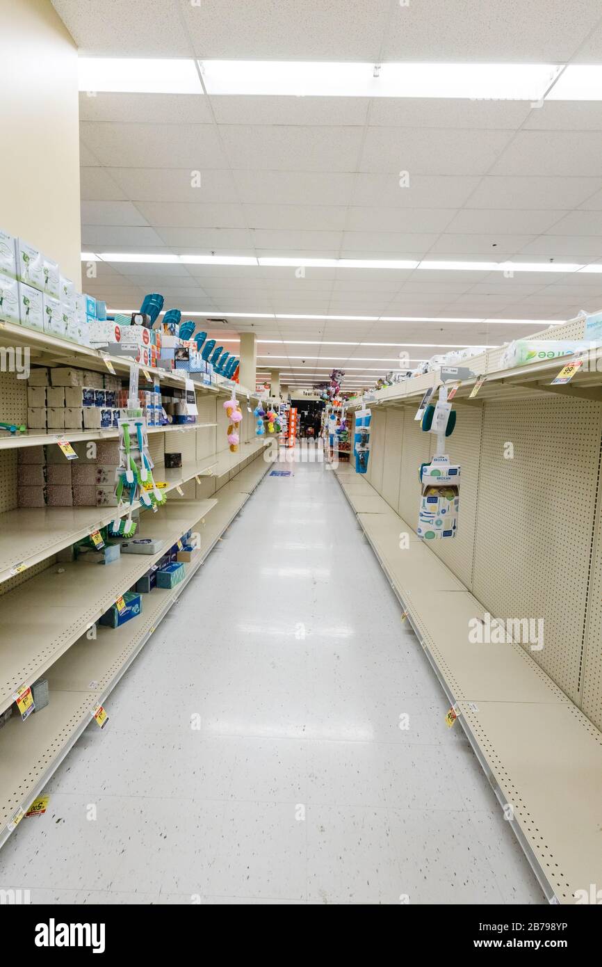 Scaffali vuoti in un supermercato negozio di alimentari nel corridoio acqua in bottiglia come coronavirus causa paura e panico Foto Stock