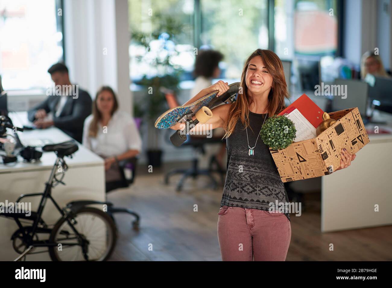 Lavoro Opportunity.Smiling donna con roba scatola lasciando edificio ufficio. Foto Stock