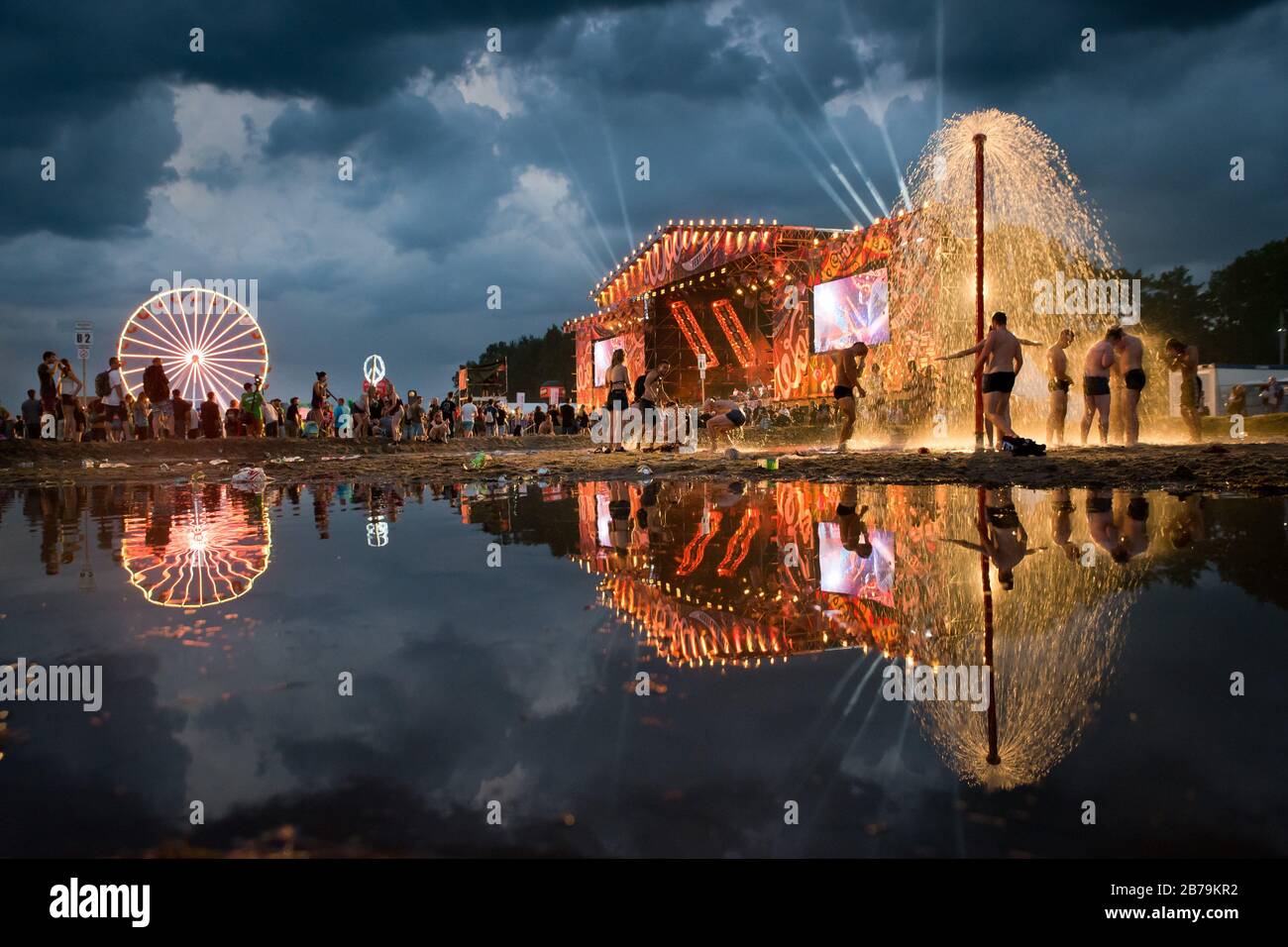 KOSTRZYN NAD ODRA, POLONIA - 3 AGOSTO 2017: Festival Przystanek Woodstock - ventilatori bagno nel fango di fronte al palco con riflessione sull'acqua. Foto Stock