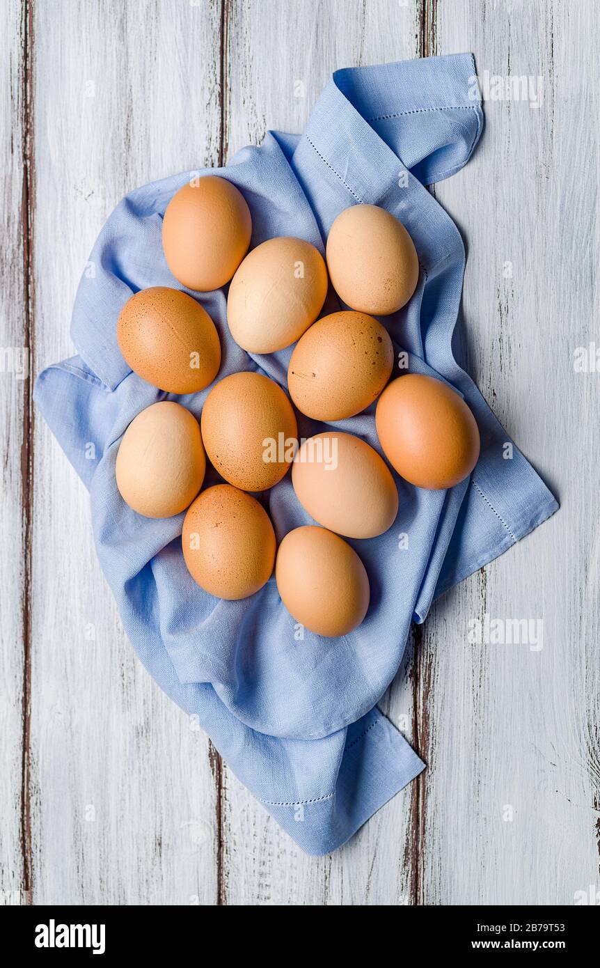Alcuni ggs di galline su delicato tovagliolo blu su sfondo bianco legno Foto Stock