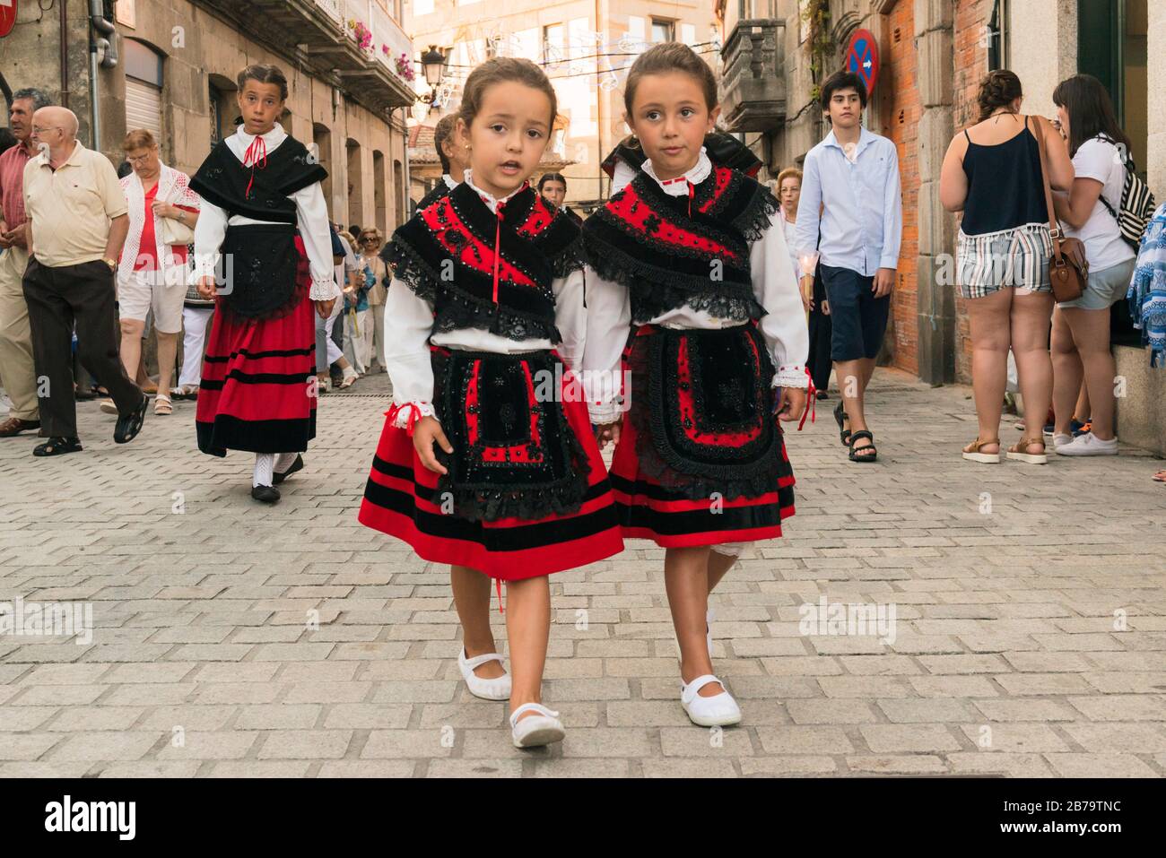 Giovani ragazze che indossano costume tradizionale partecipando alla processione serale che pareggia la statua di Cristo afflitto durante Fiestas de Bouzas. Vigo Foto Stock