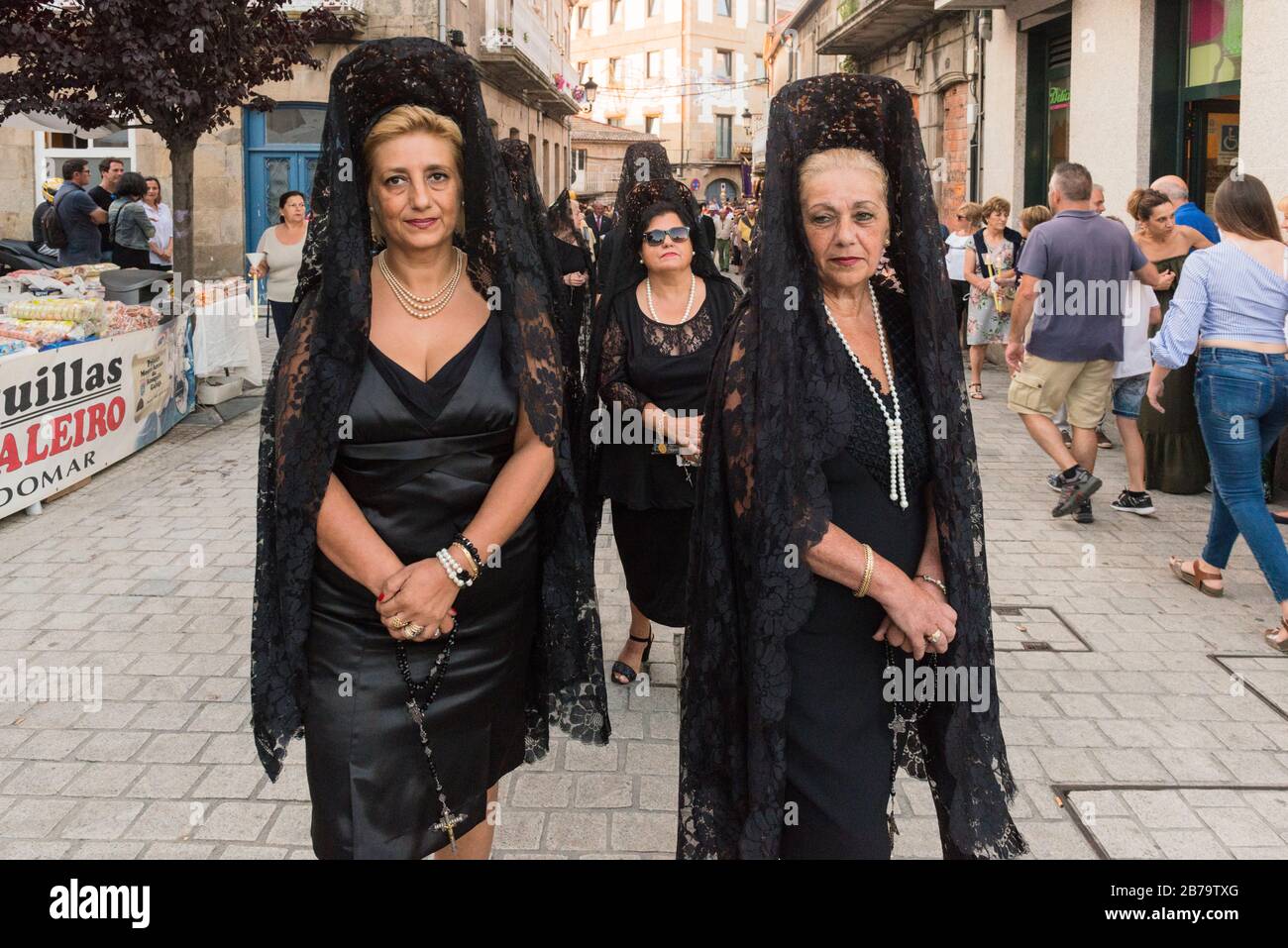 Donne che indossano abiti neri tradizionali e mantilla (veli di merletto), parte della processione religiosa durante Fiestas de Bouzas, Vigo. Foto Stock