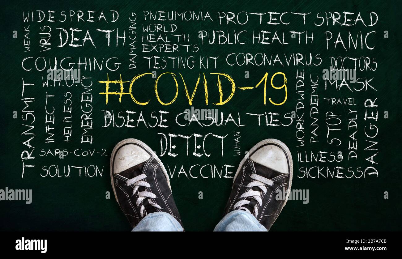 Persona in piedi sulla lavagna con n. COVID-19 nuvola di parole. Concetto di mondiale coronavirus pandemico. Foto Stock
