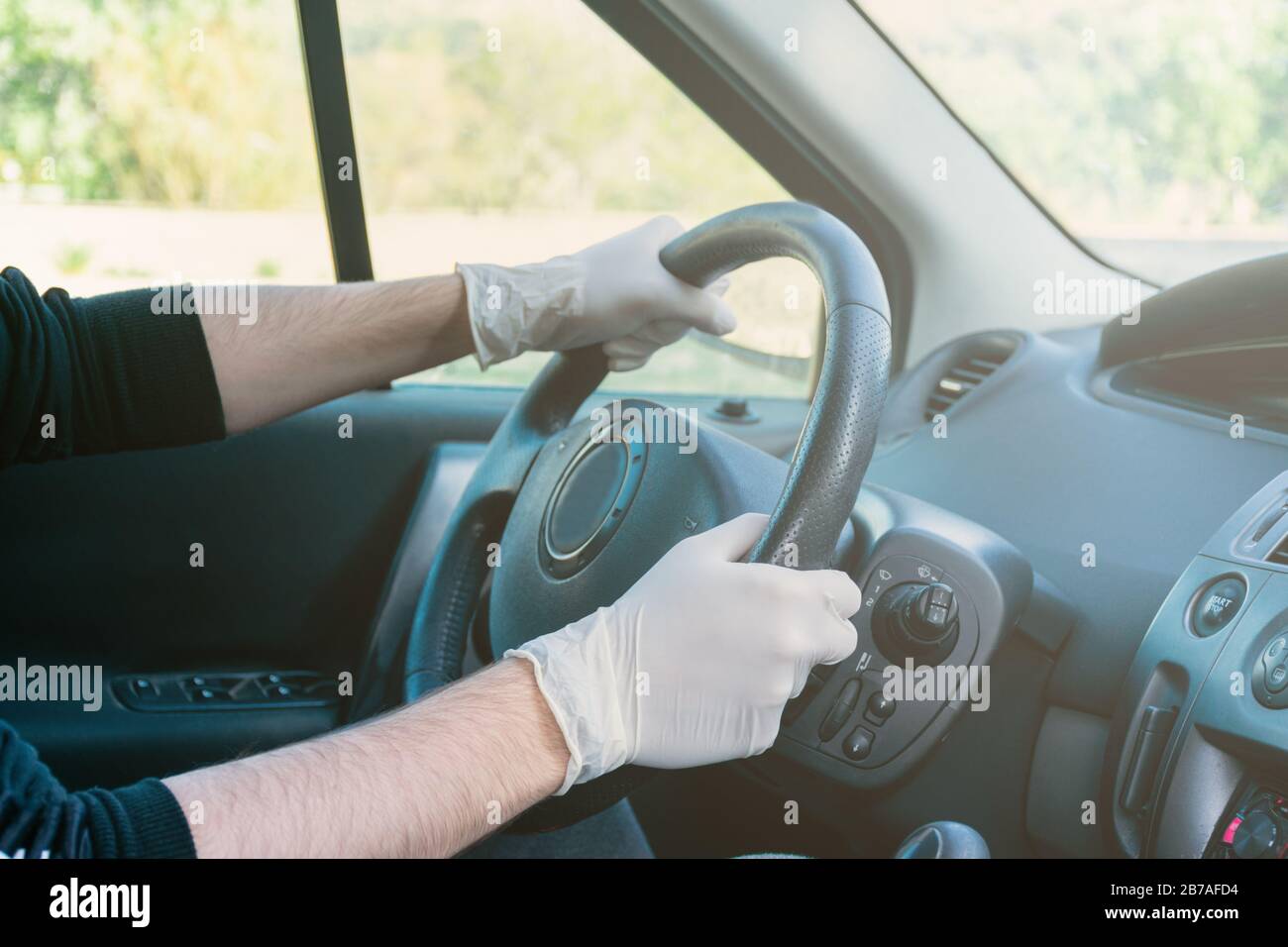 Mani che tengono il volante di una vettura durante la guida con guanti in  lattice per evitare contagio Foto stock - Alamy