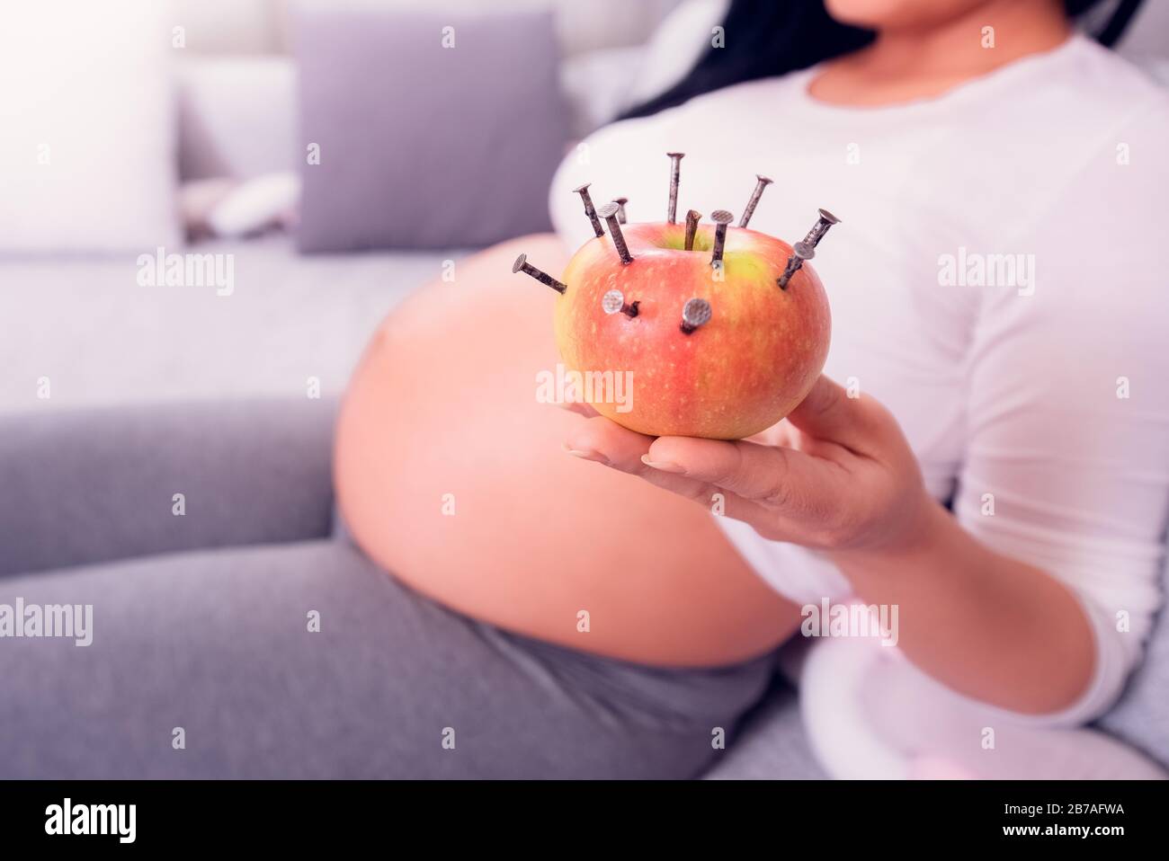 Donna incinta che mangia mela farcita con unghie di legno per aumentare il livello di ferro nel sangue. Trattamento vecchio stile per aumentare l'emoglobina. Foto Stock
