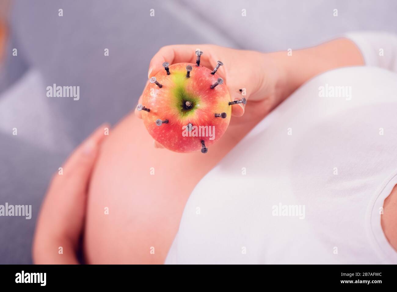 Donna incinta che mangia mela farcita con unghie di legno per aumentare il livello di ferro nel sangue. Trattamento vecchio stile per aumentare l'emoglobina. Foto Stock