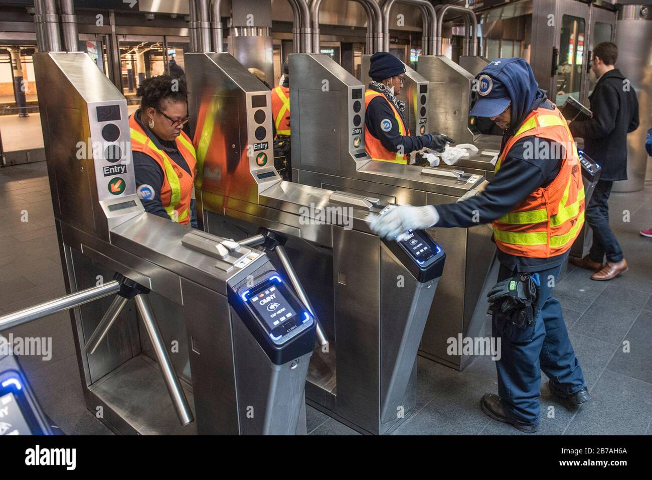 I lavoratori della Metropolitan Transportation Authority disinfettano e sanitizzano i tornelli della stazione per prevenire il COVID-19, coronavirus nel sistema della metropolitana di New York City Transit 12 marzo 2020 a New York City, New York. Foto Stock