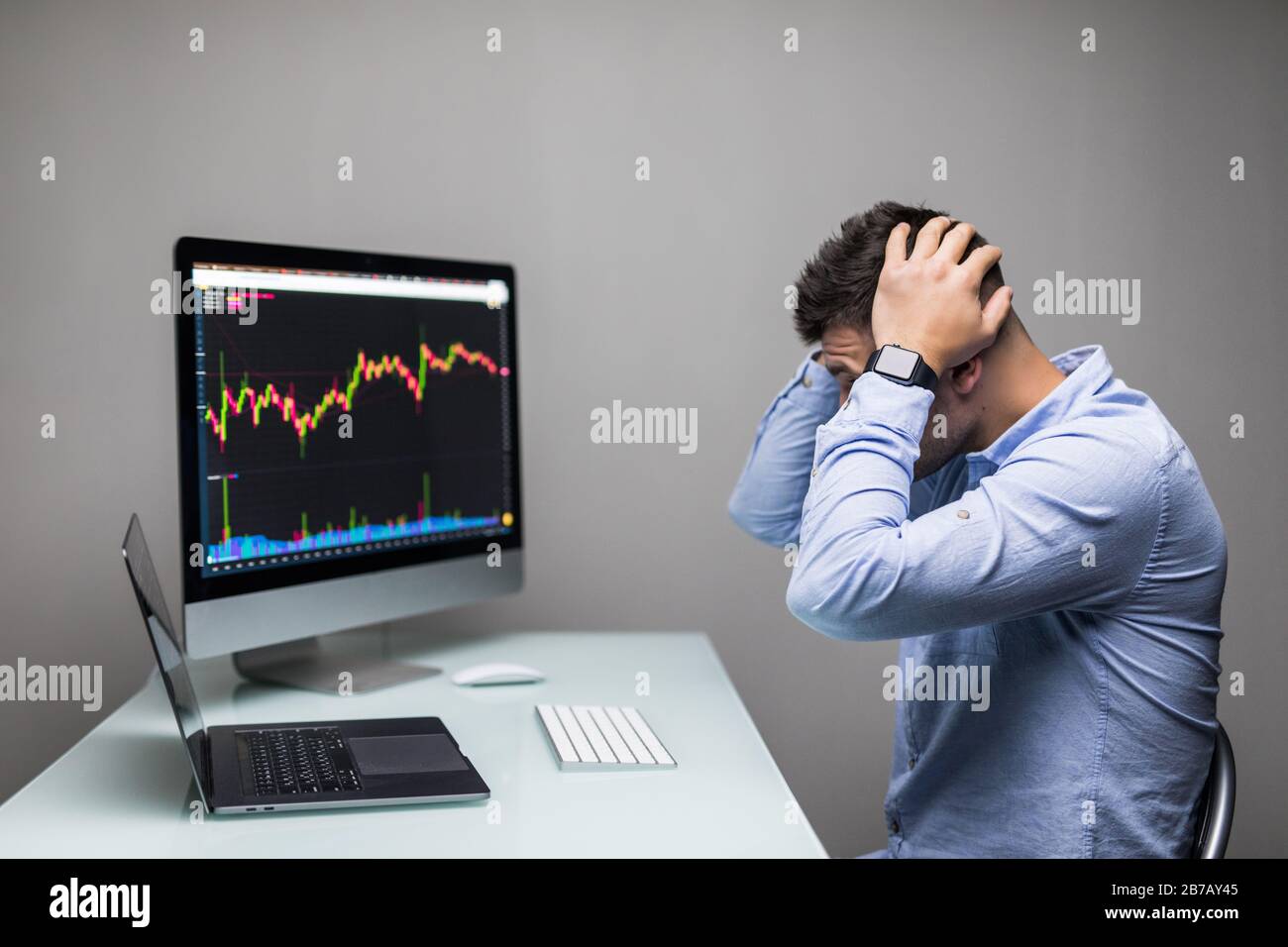 Uomo che lamenta con le mani sulla testa di fronte al computer con il grafico del business infruttuoso sullo schermo. Foto Stock