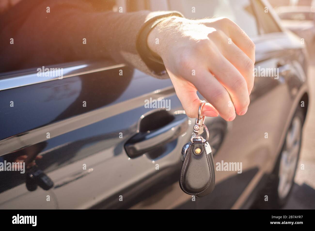 L'uomo in macchina ha messo la mano fuori e tiene le chiavi. Primo piano. Foto Stock