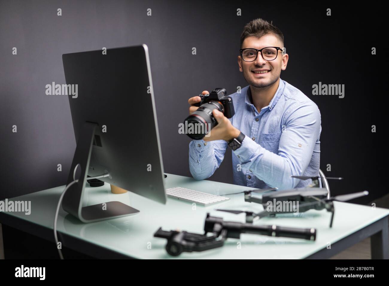 Fotografo in ufficio a lavorare sul computer desktop Foto Stock