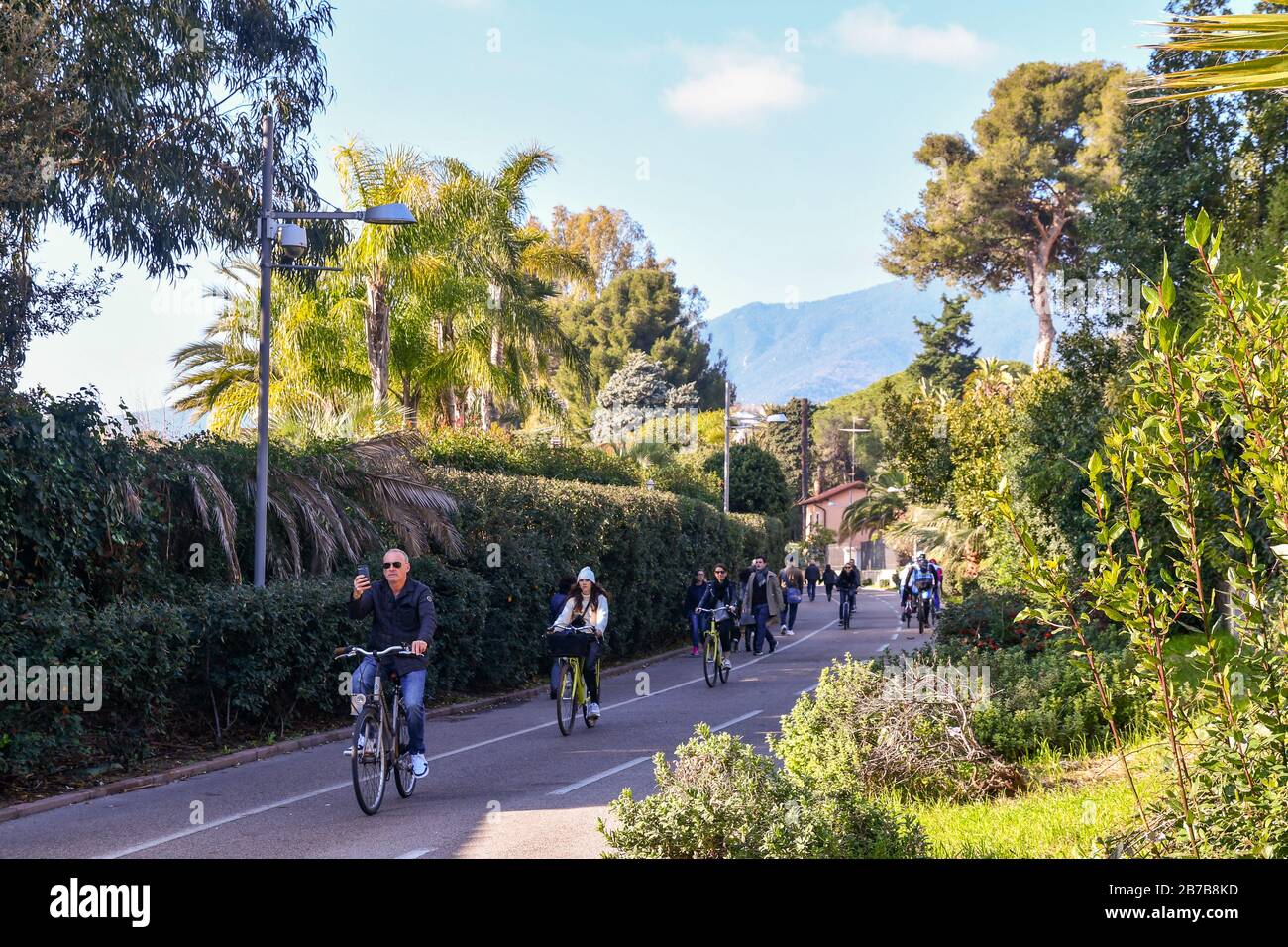 Persone e turisti a piedi e in bicicletta sulla pista ciclabile della Riviera Ligure dei Fiori in una giornata di sole, Sanremo, Liguria, Italia Foto Stock