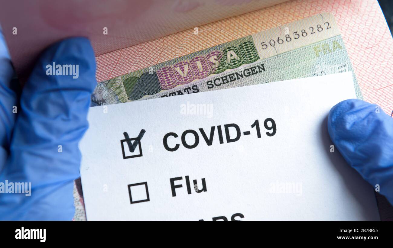COVID-19 coronavirus pandemico e concetto di viaggio, marchio positivo COVID-19 e visto Schengen timbro. Controllo del passaporto dei turisti con controllo del coronavirus. Foto Stock