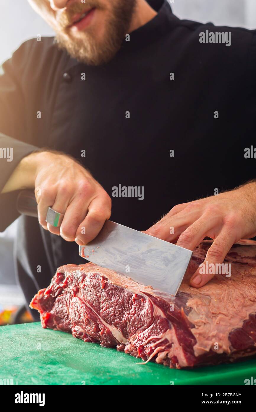 Chef in nero indossare in cucina è il taglio di carne di manzo a coltello Foto Stock