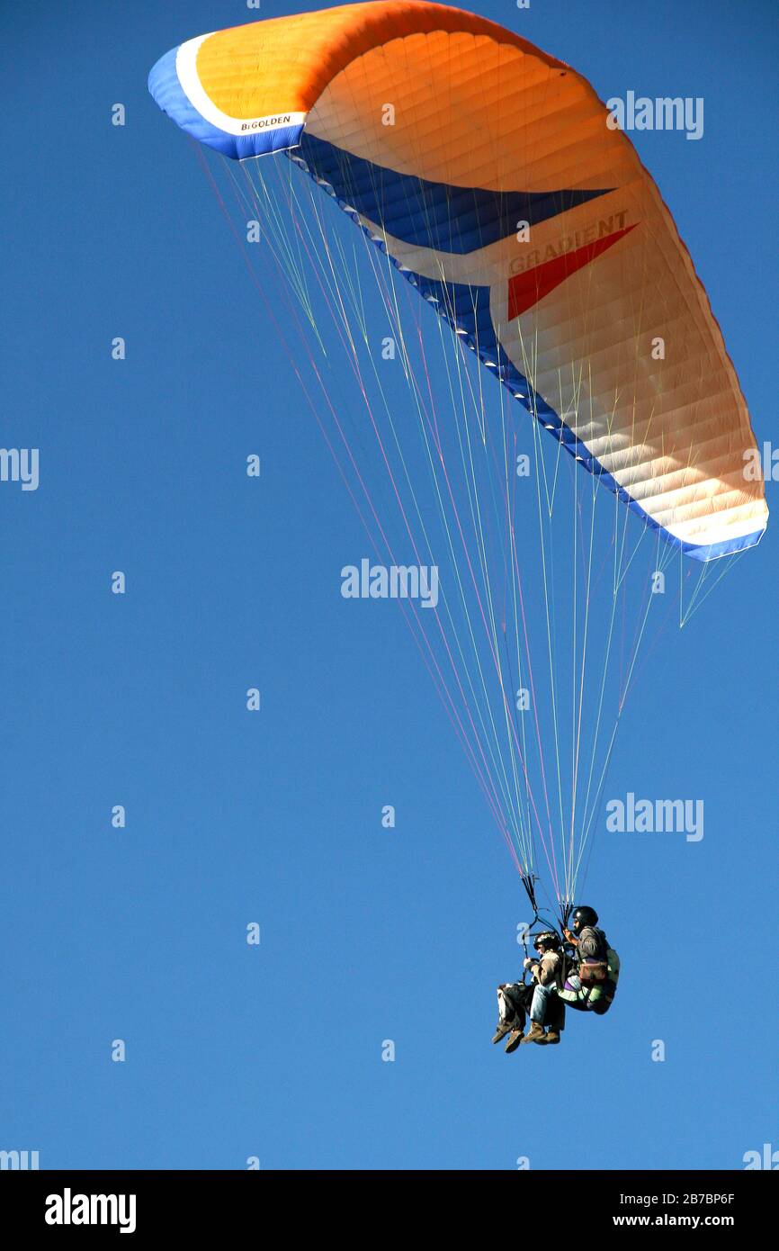 Parapendio tandem con paracadute giallo arancio bianco e blu a Oludeniz in Turchia Foto Stock