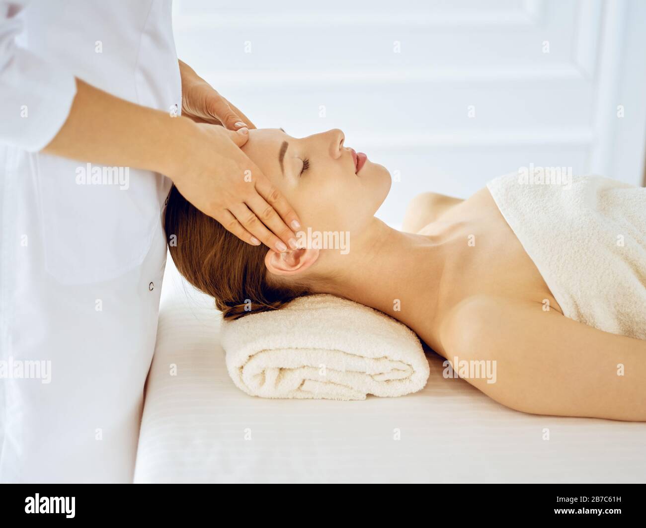Bella donna che si gode massaggio viso con occhi chiusi. Trattamento  termale in medicina Foto stock - Alamy