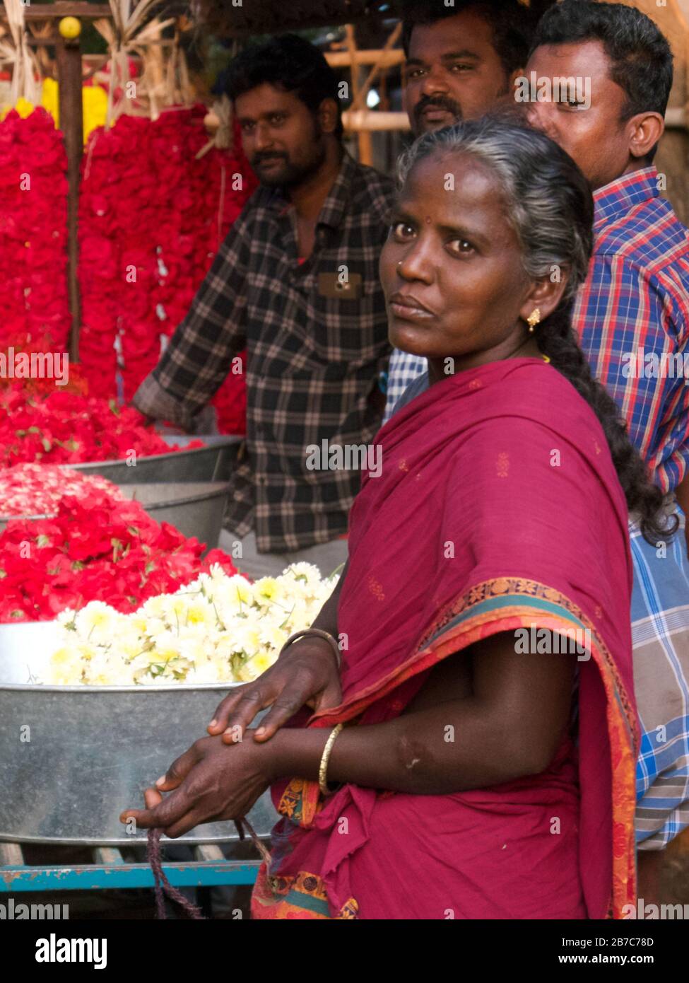 Una donna che fa e vende coloratissime ghirlande di fiori che sono offerte prese ai templi indù dai fedeli, Tamil Nadu, India meridionale Foto Stock