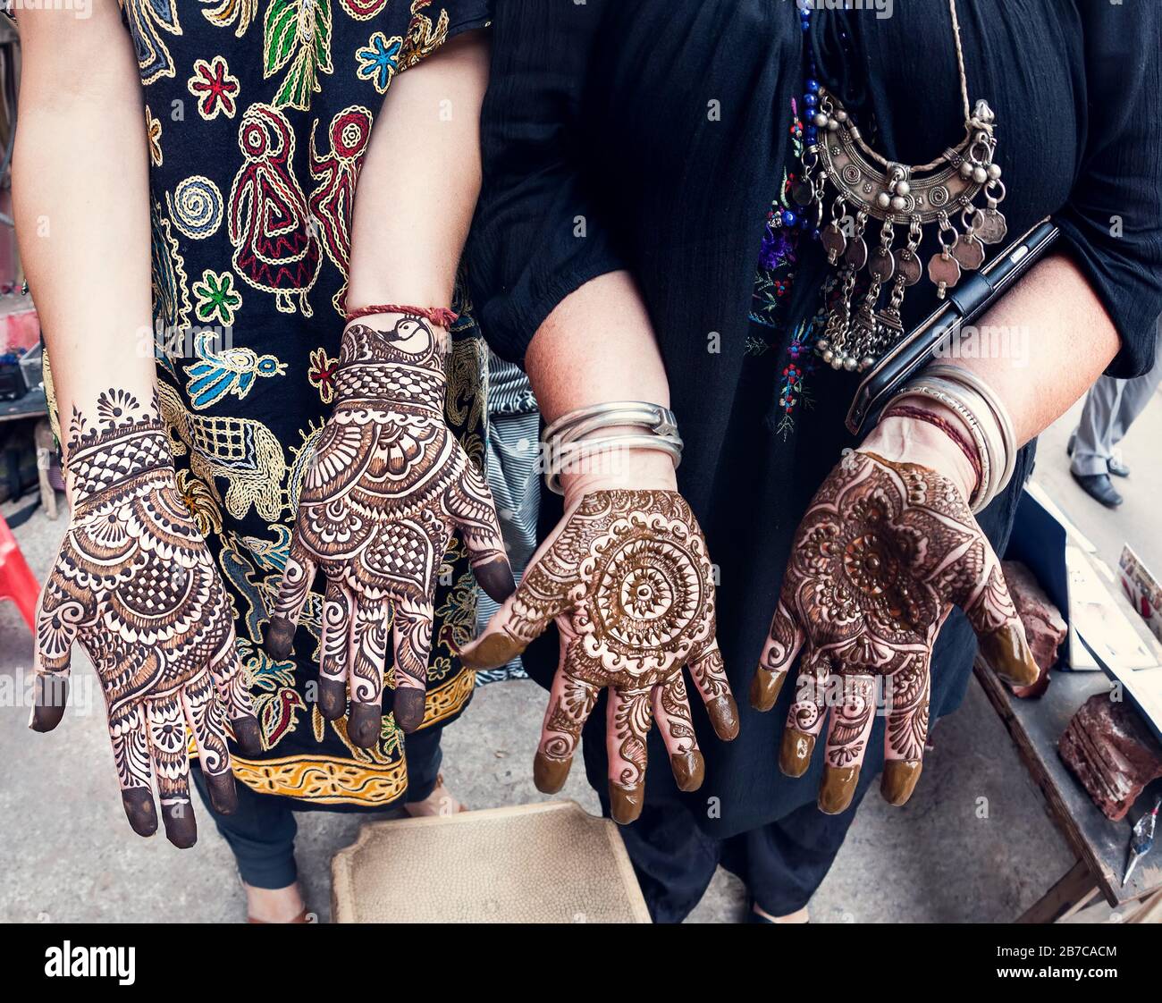 Donna turistica che li mostra mani con tradizionale henné pittura mehendi alla strada principale bazar a Delhi Foto Stock