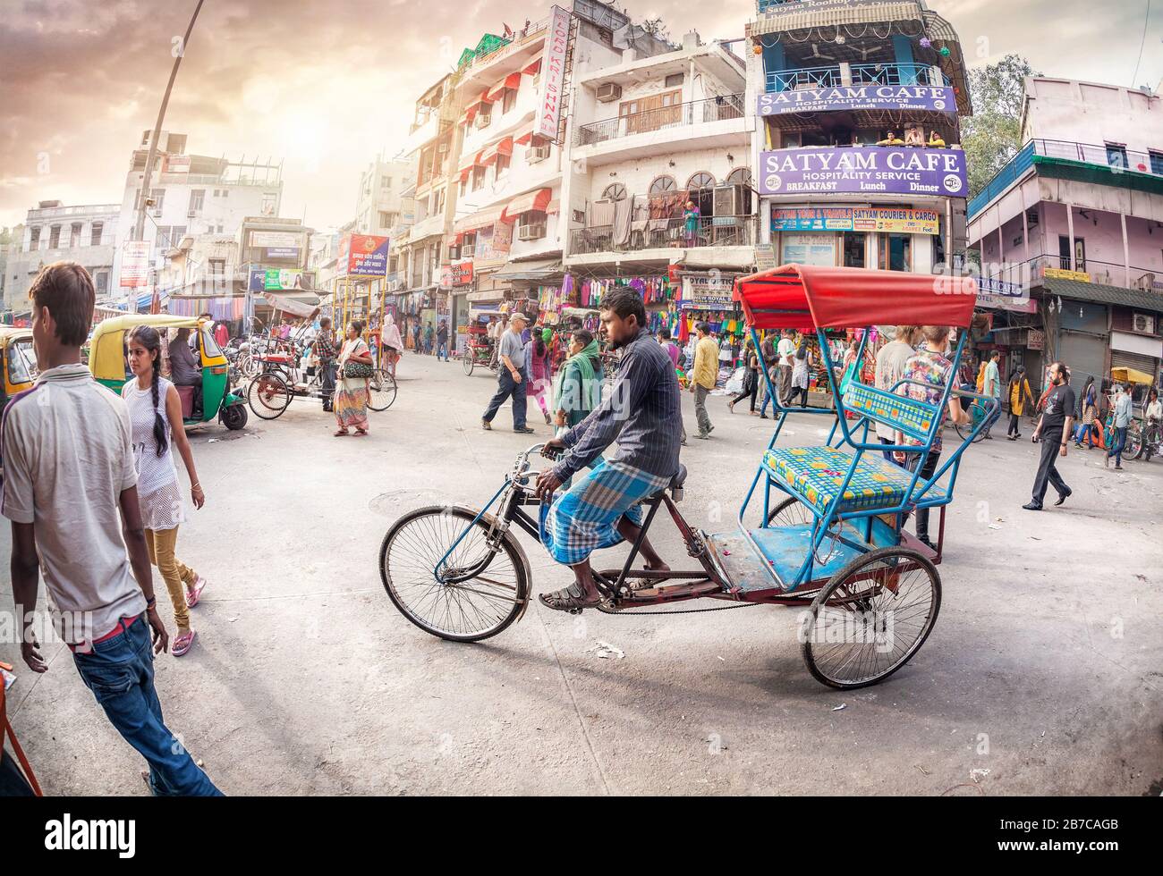 New DELHI, INDIA - 23 FEBBRAIO 2015: Conducente di risciò in strada affollata con negozi, hotel, trasporti e persone nel Bazaar principale, Paharganj Foto Stock
