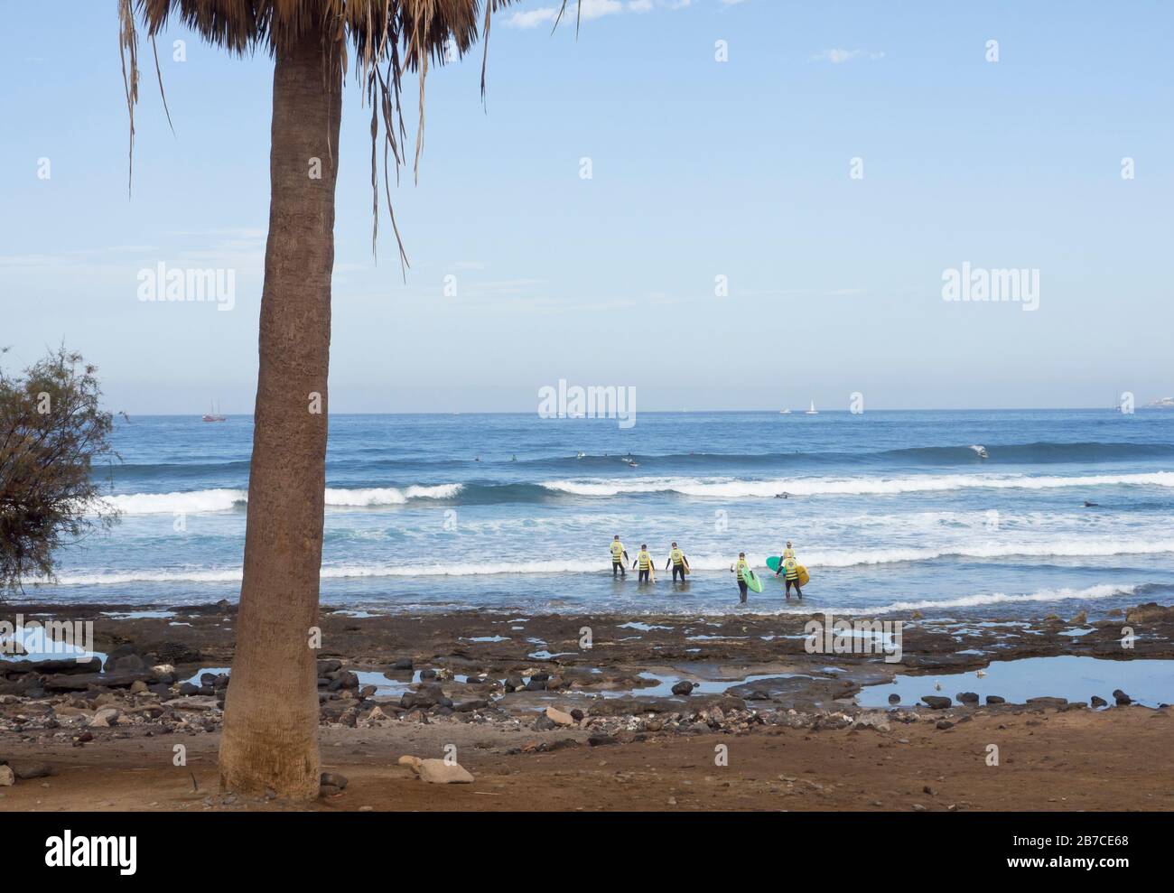 Un gruppo di turisti che si tuffano nell'oceano Atlantico per imparare a navigare le onde, Playa de las americas, Tenerife Isole Canarie Spagna Foto Stock
