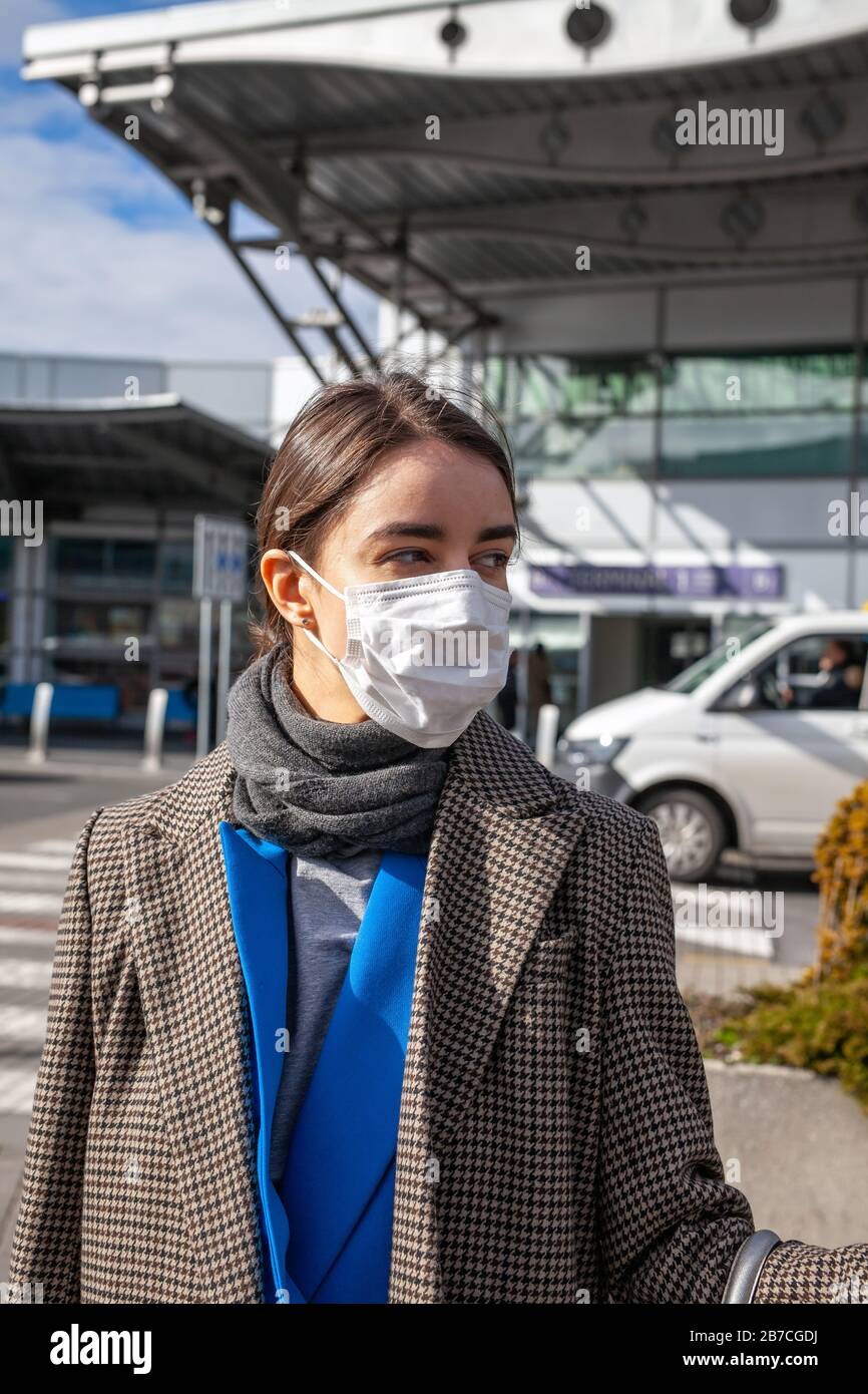 Young Woman in Face Mask all'ingresso dell'aeroporto Foto Stock