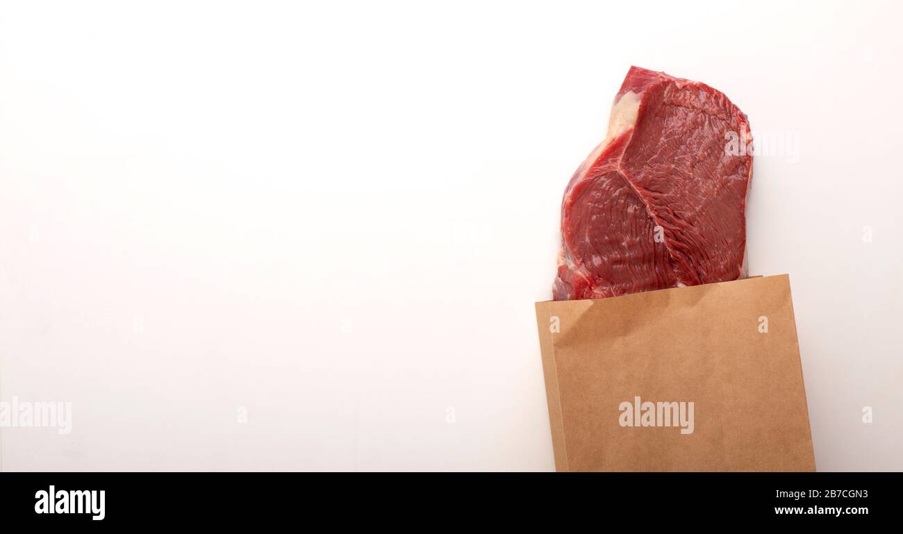 Carne cruda in sacchetto di carta su sfondo grigio Foto Stock