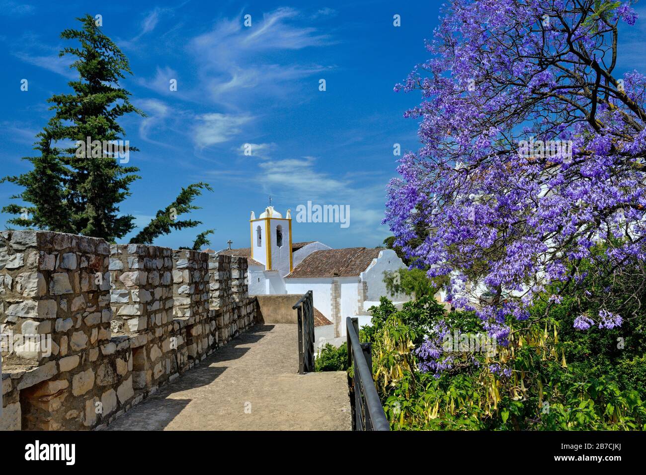 Portogallo, l'Algarve, castello di Tavira merlements con alberi jacaranda in fiore Foto Stock