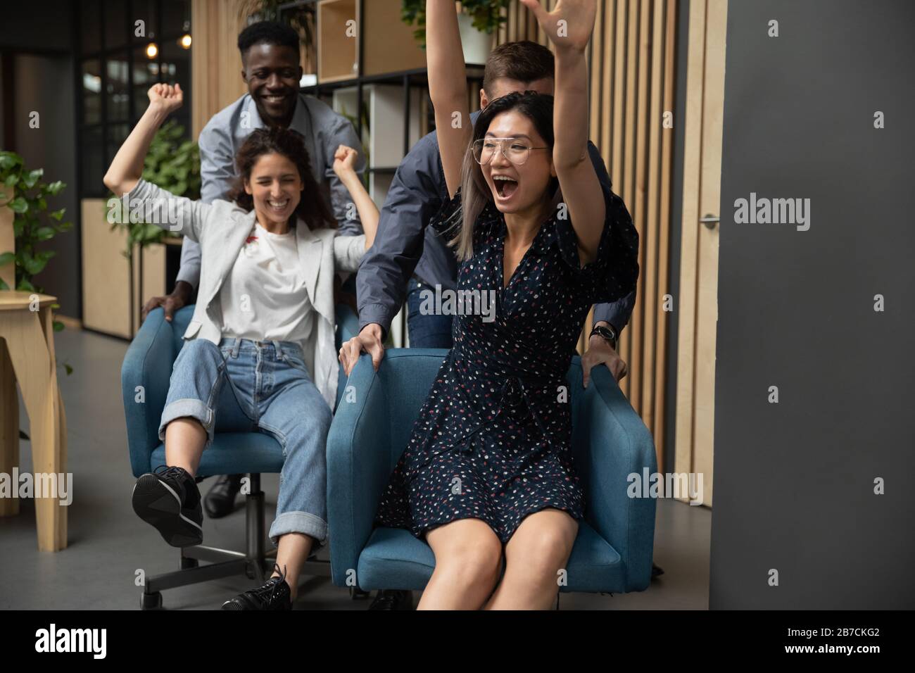 Eccitate donne d'affari che viaggiano su sedie, diversi colleghi che si divertono Foto Stock