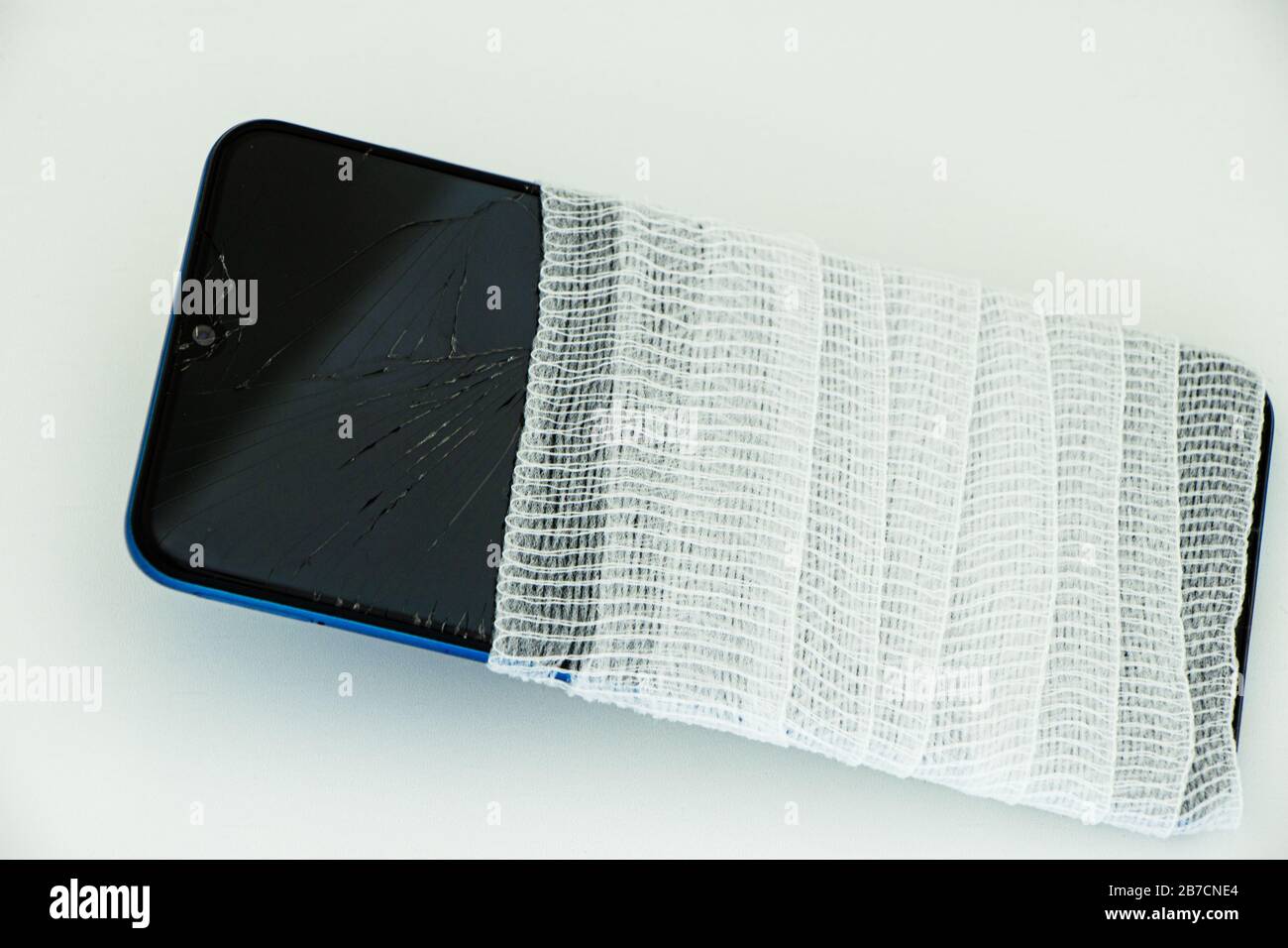 Concetto di smartphone rotto in bendaggio con sfondo bianco, crepe Foto Stock