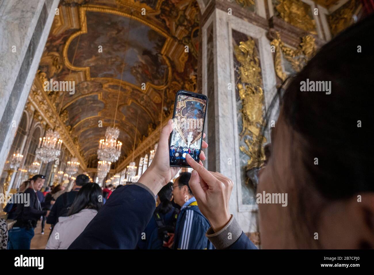 Turista che prende una foto del telefono cellulare del soffitto della Sala degli specchi al Palazzo di Versailles nella periferia di Parigi, Francia, Europa Foto Stock