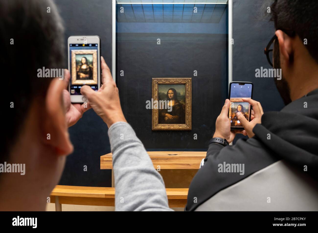 Due turisti che usano i loro smartphone per scattare foto della pittura della Monna Lisa dell'artista Leonardo da Vinci, Museo del Louvre, Parigi, Francia, Europa Foto Stock